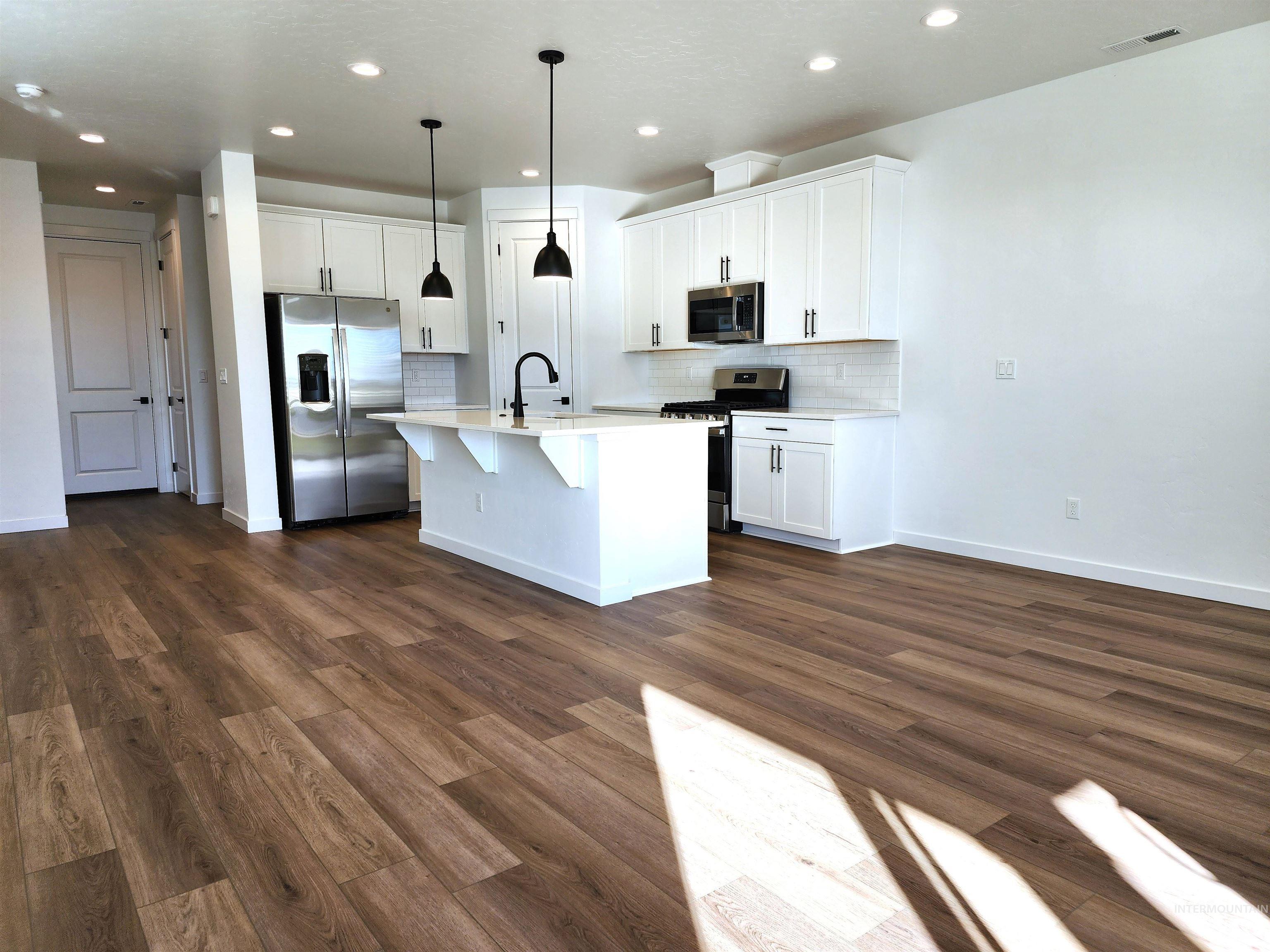 Kitchen with appliances with stainless steel finishes, backsplash, a center island with sink, white cabinets, and recessed lighting