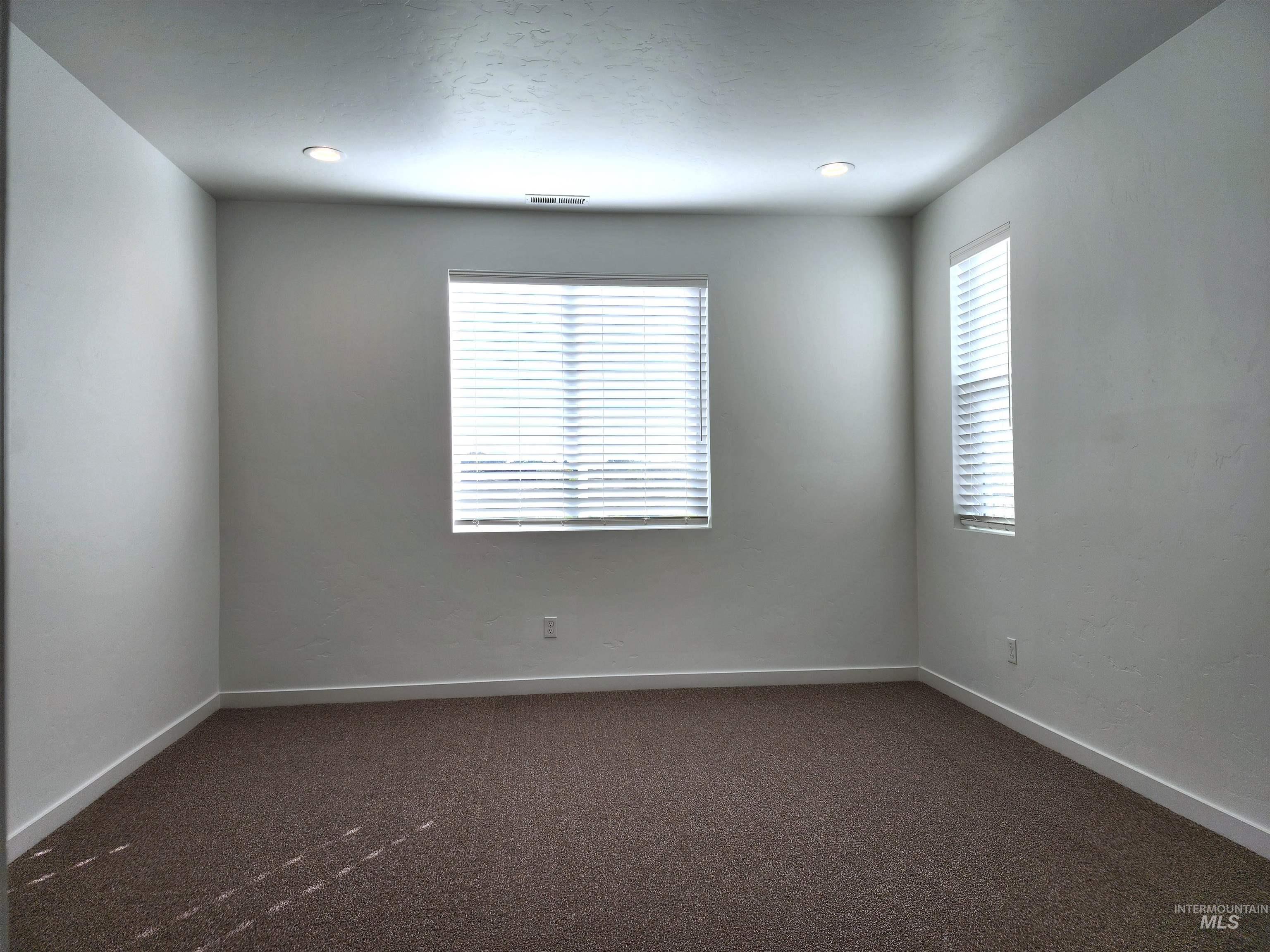Unfurnished room featuring dark carpet and baseboards