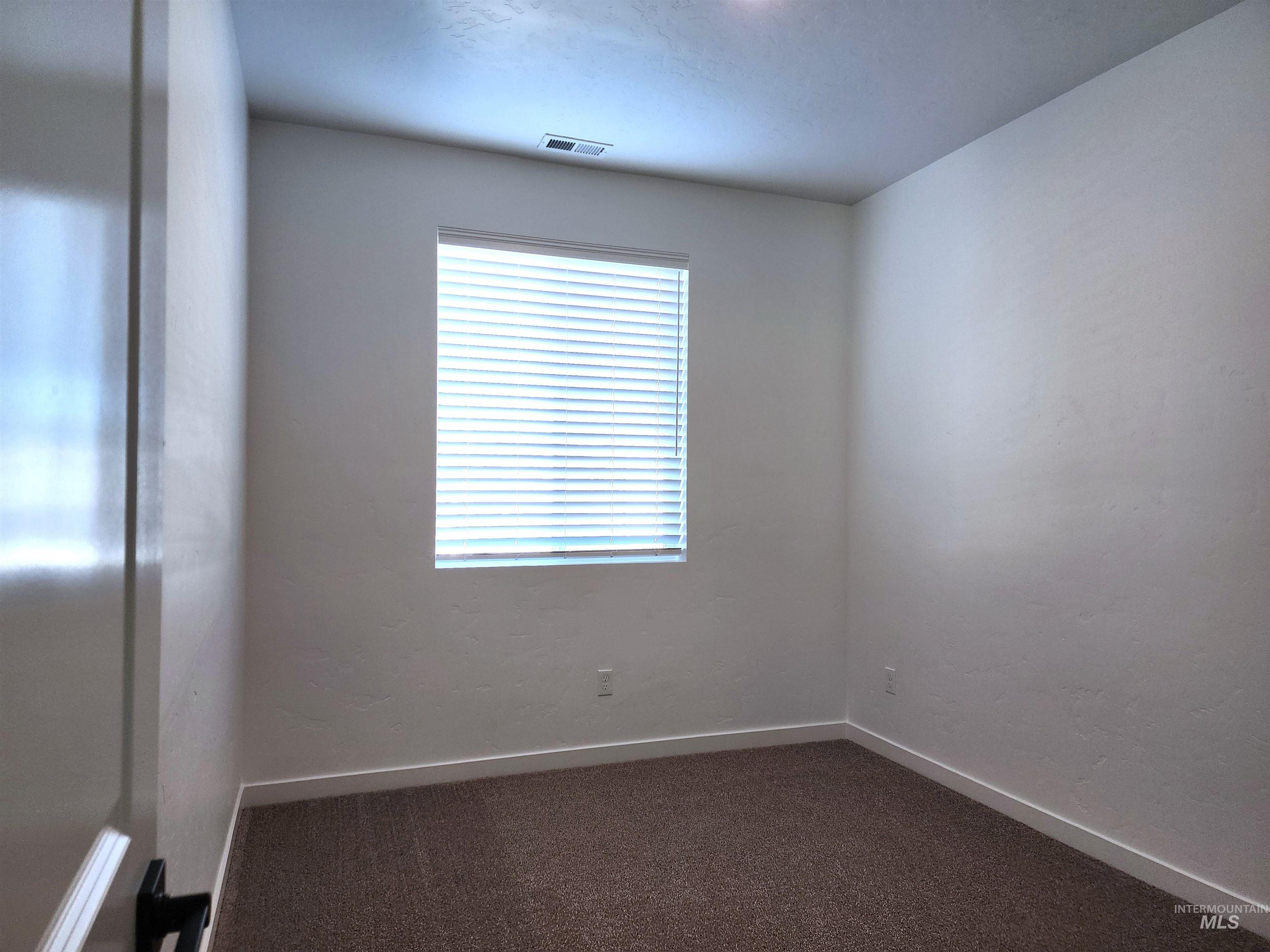 Spare room featuring dark carpet and baseboards