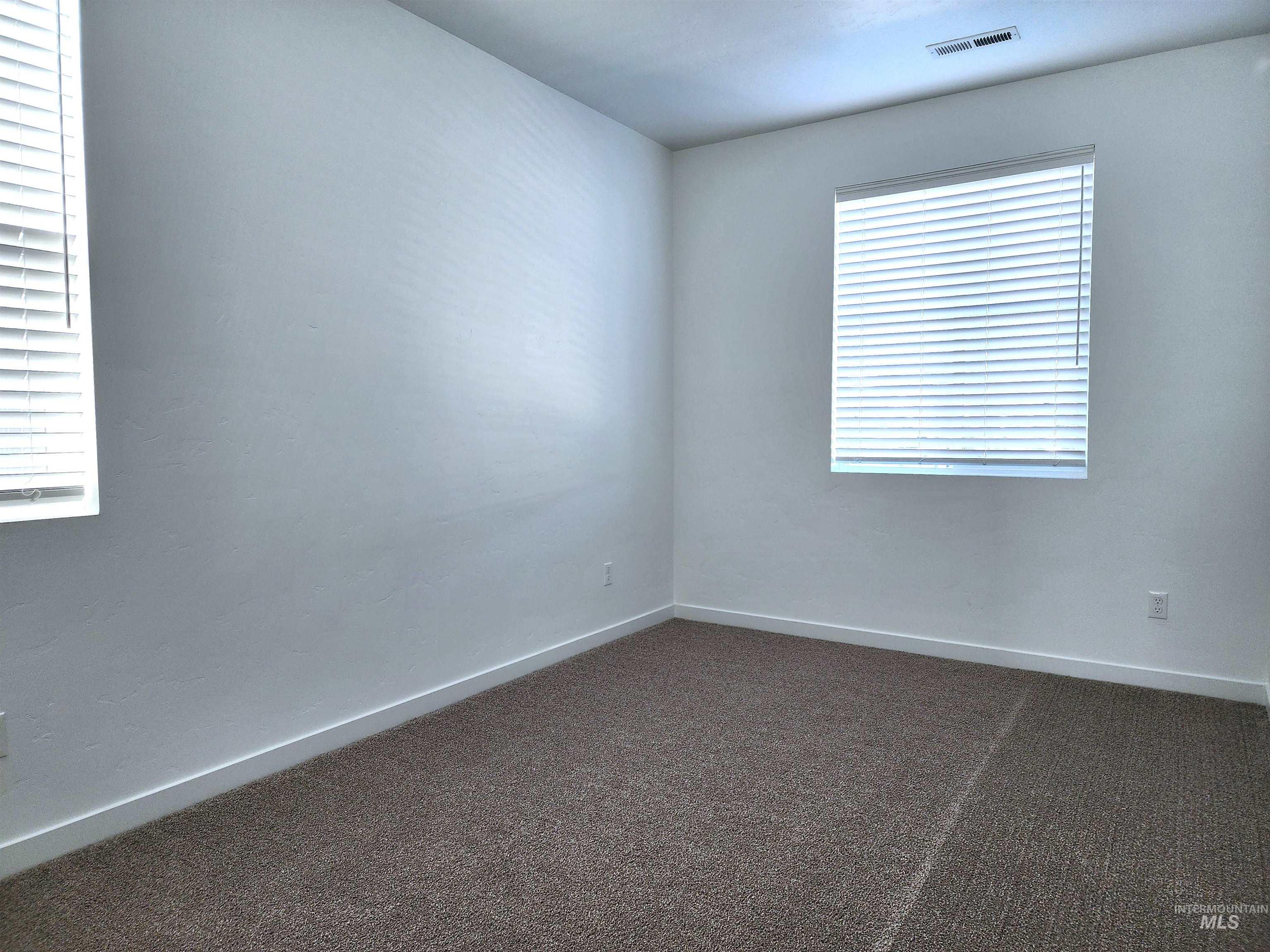 Unfurnished room with dark carpet and baseboards