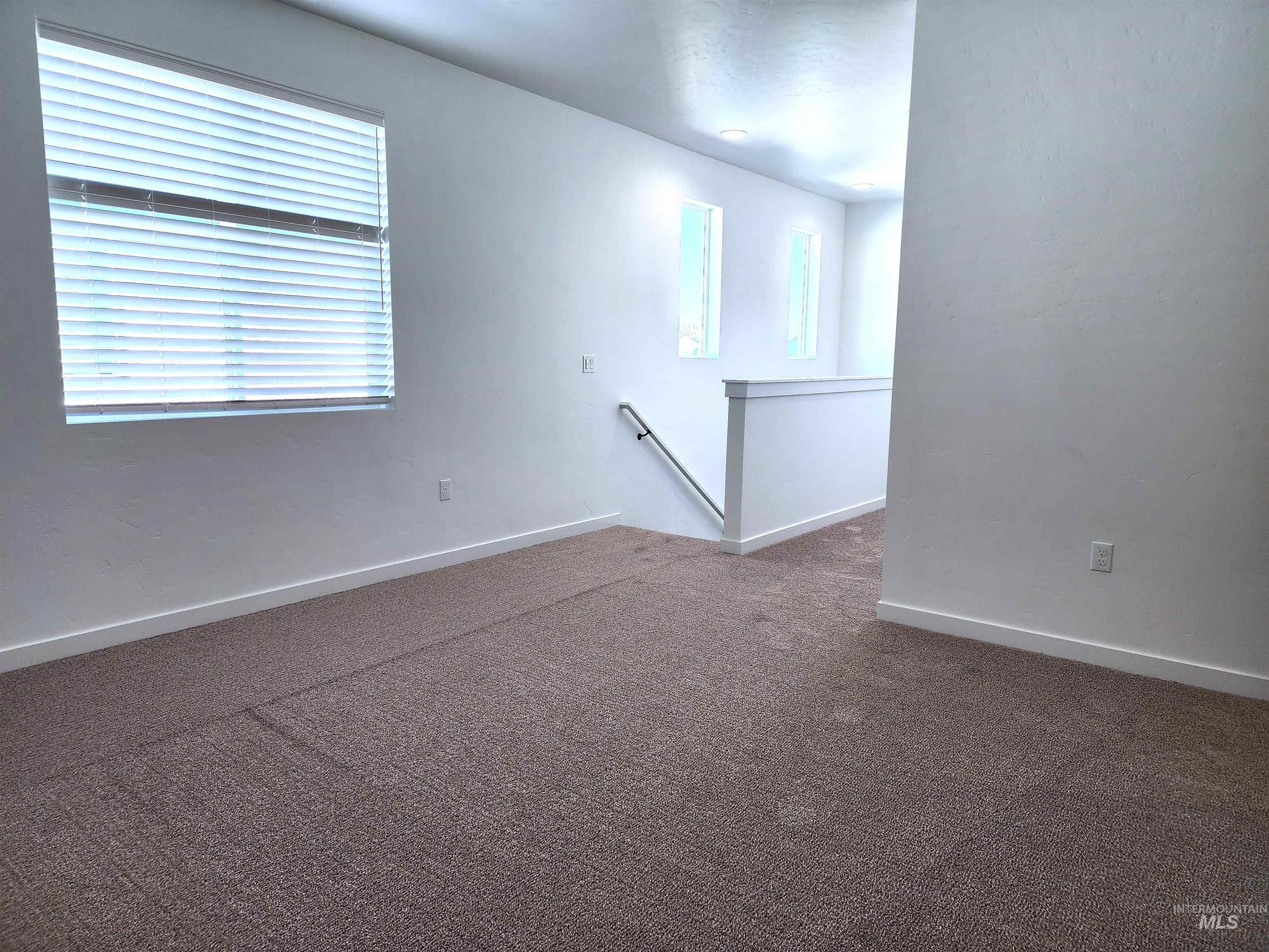 Empty room with dark carpet and baseboards