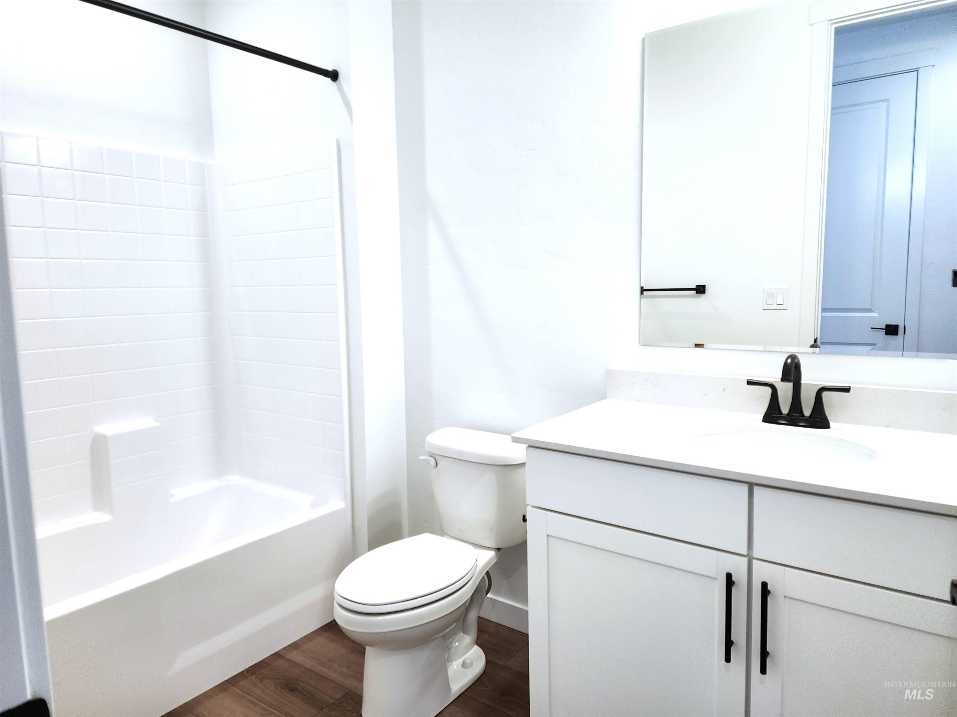 Bathroom featuring dark wood-style flooring, vanity, and shower / tub combination