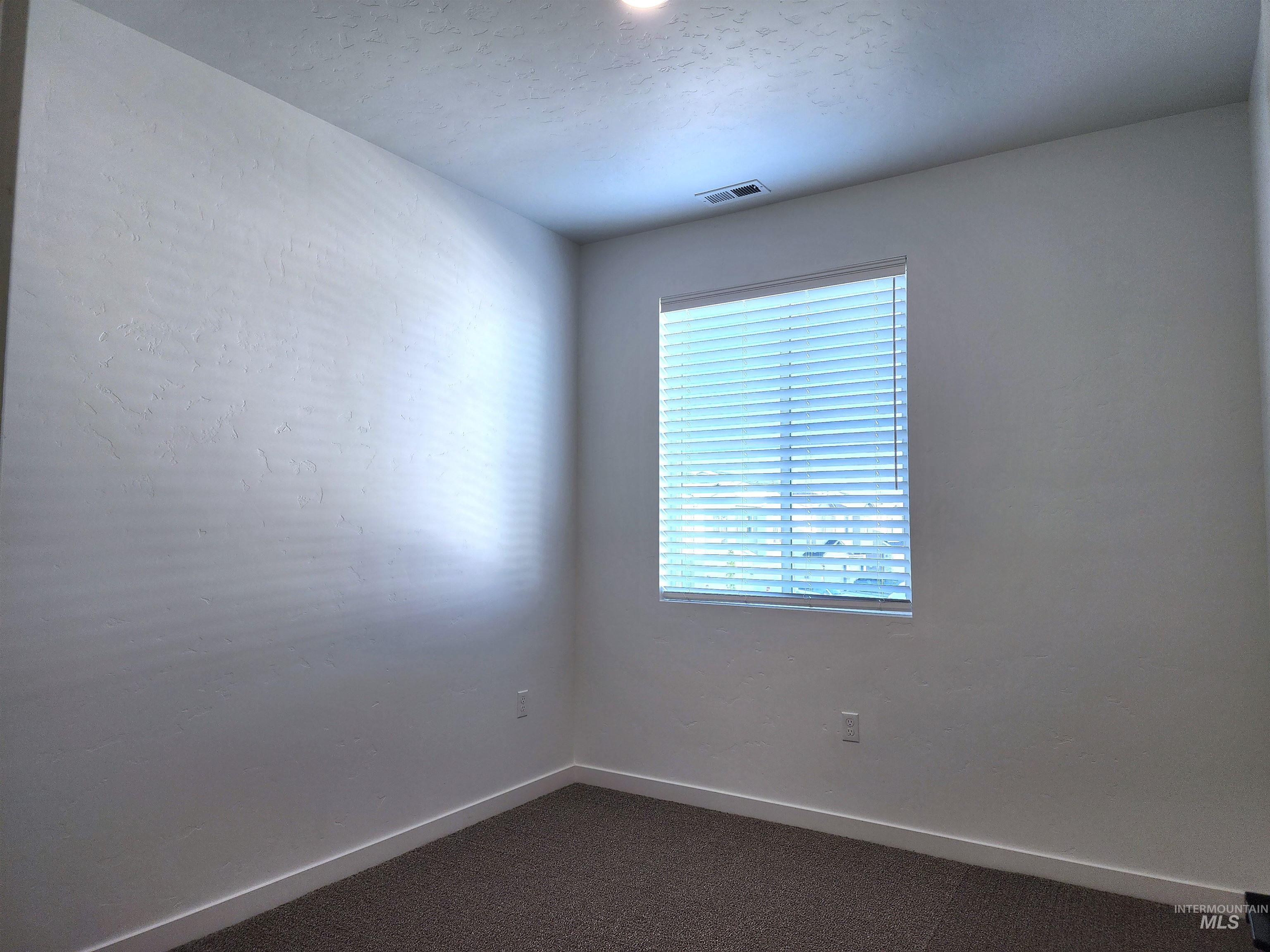 Spare room featuring dark carpet and a textured ceiling