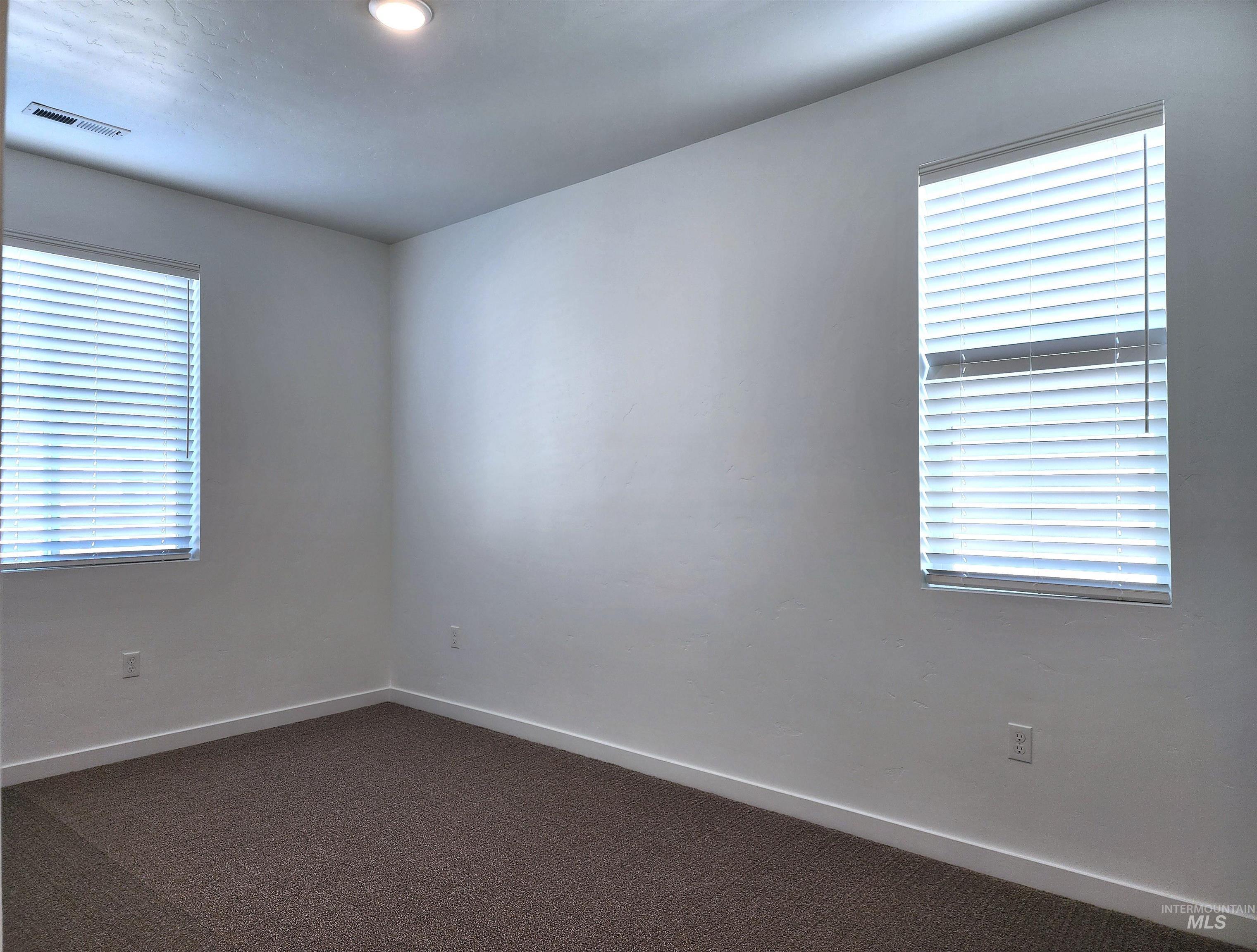 Unfurnished room with dark carpet and baseboards