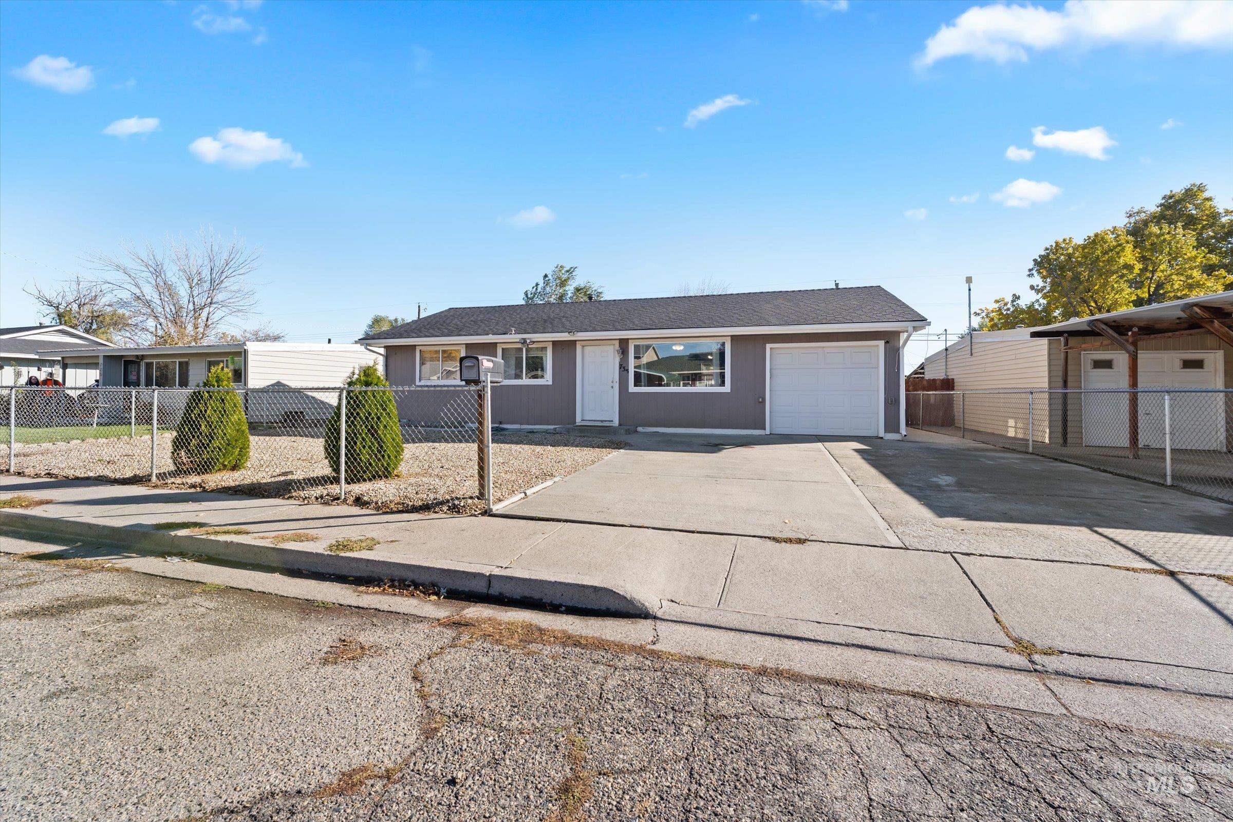 Ranch-style house with a fenced front yard, concrete driveway, and a garage