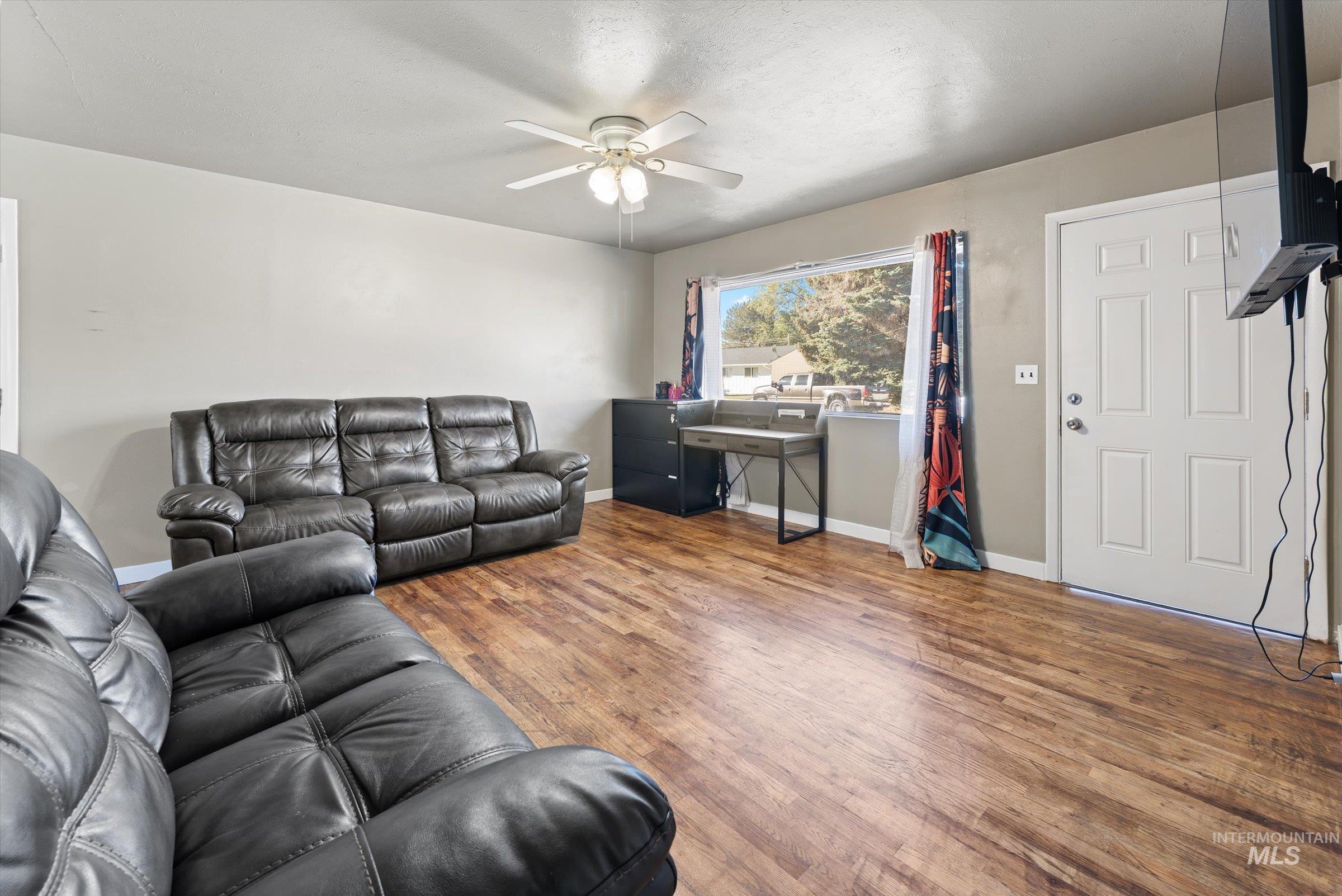Living room with wood finished floors, ceiling fan, and a textured ceiling