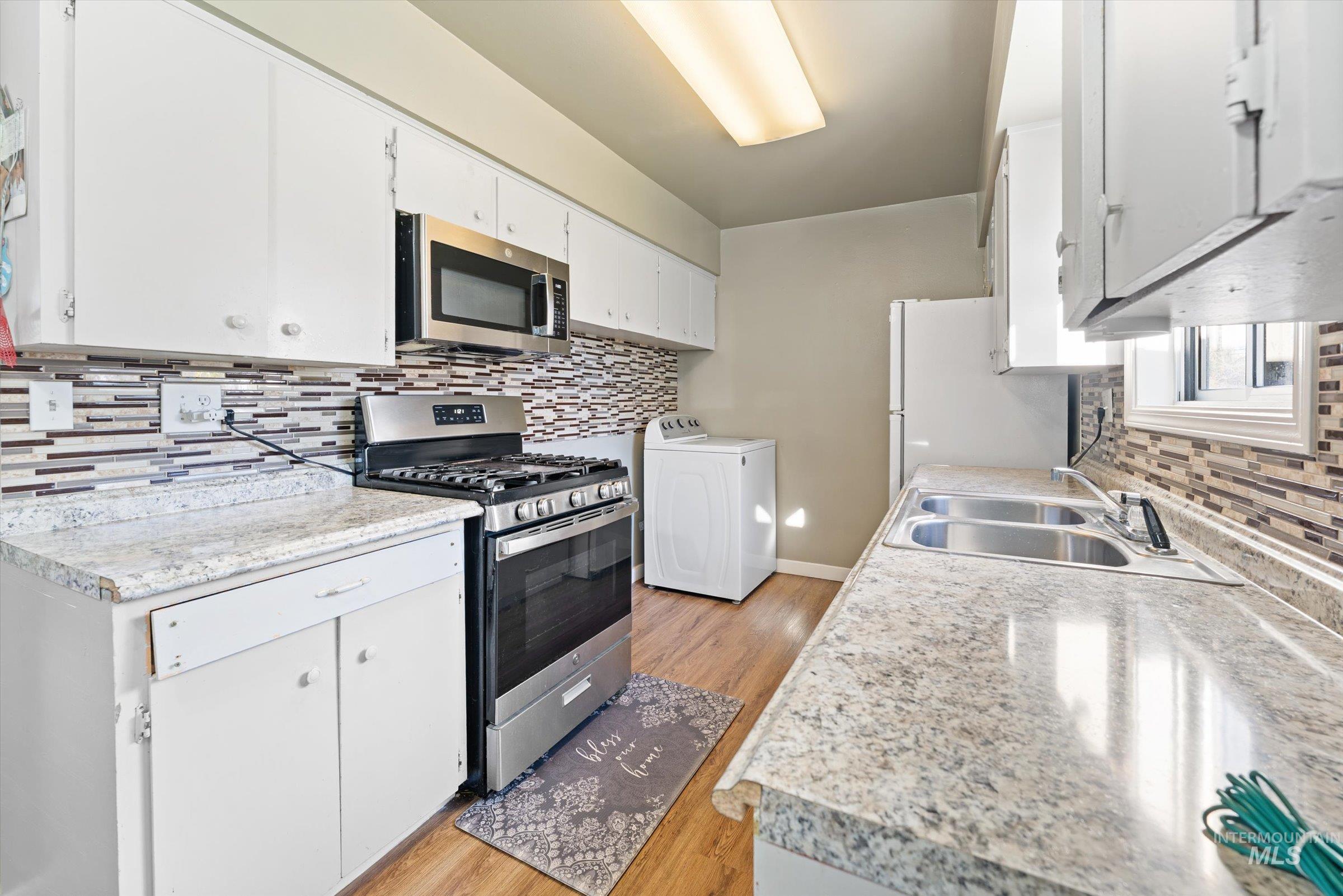 Kitchen featuring stainless steel appliances, tasteful backsplash, light countertops, and washer / dryer