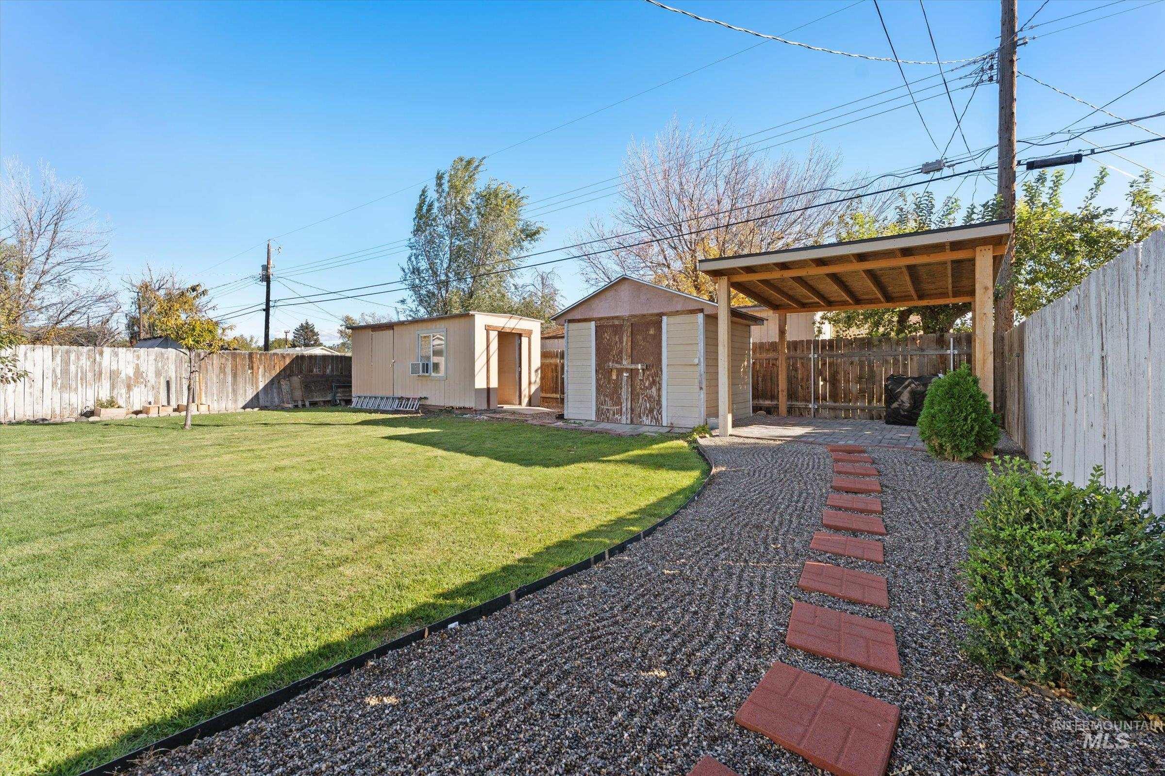 Fenced backyard featuring a storage unit