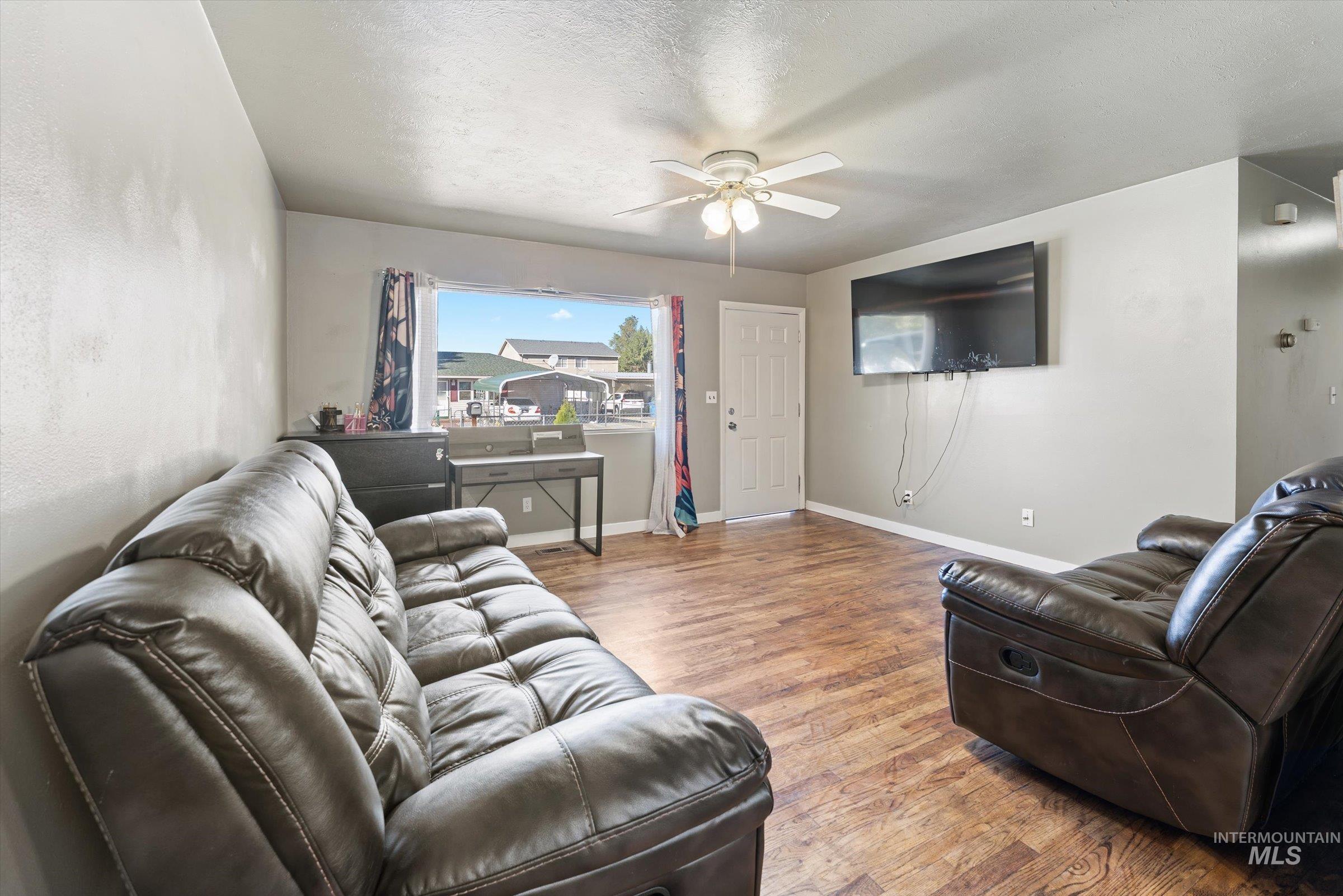 Living area with wood finished floors, a textured ceiling, and a ceiling fan