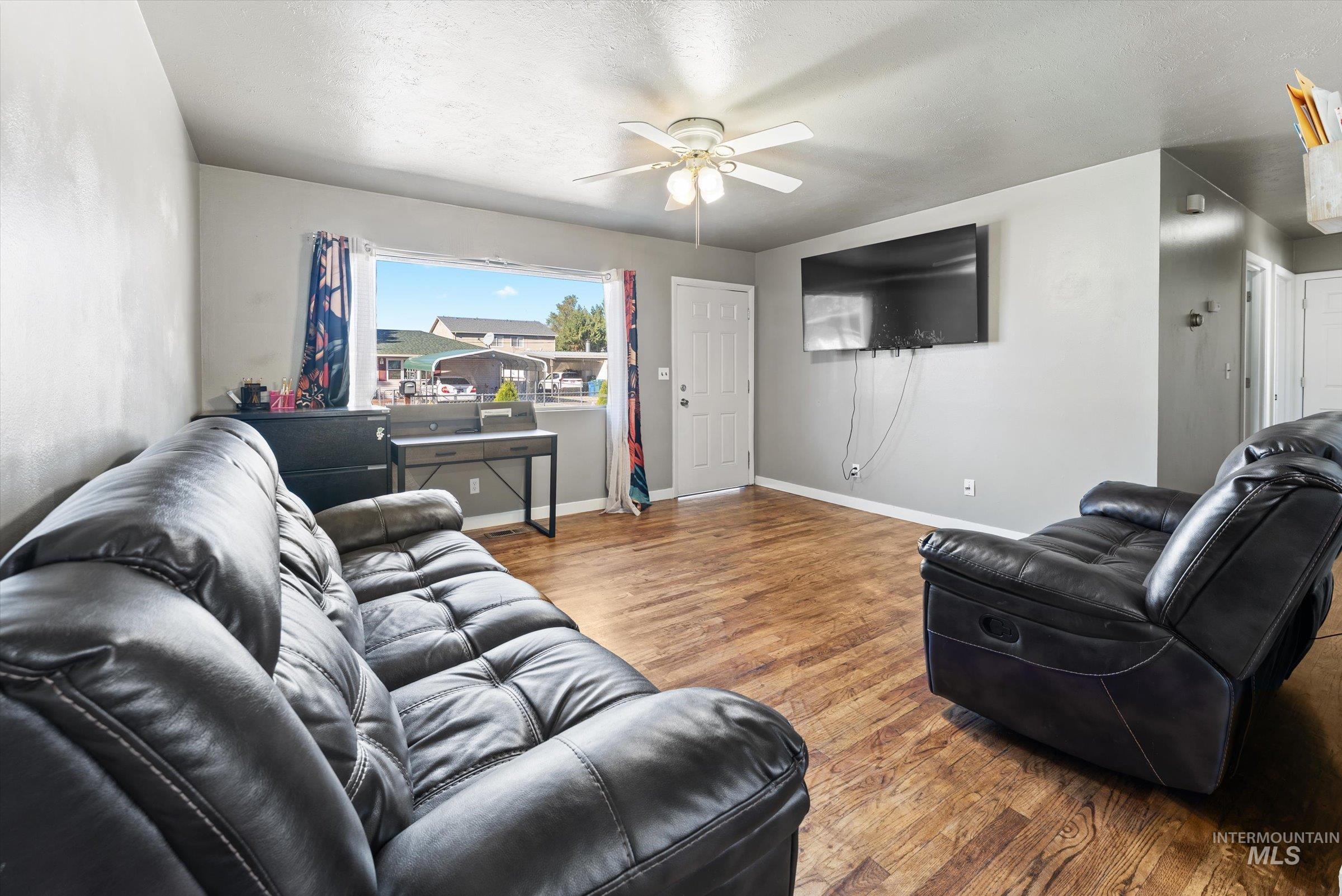 Living area with wood finished floors, ceiling fan, and a textured ceiling