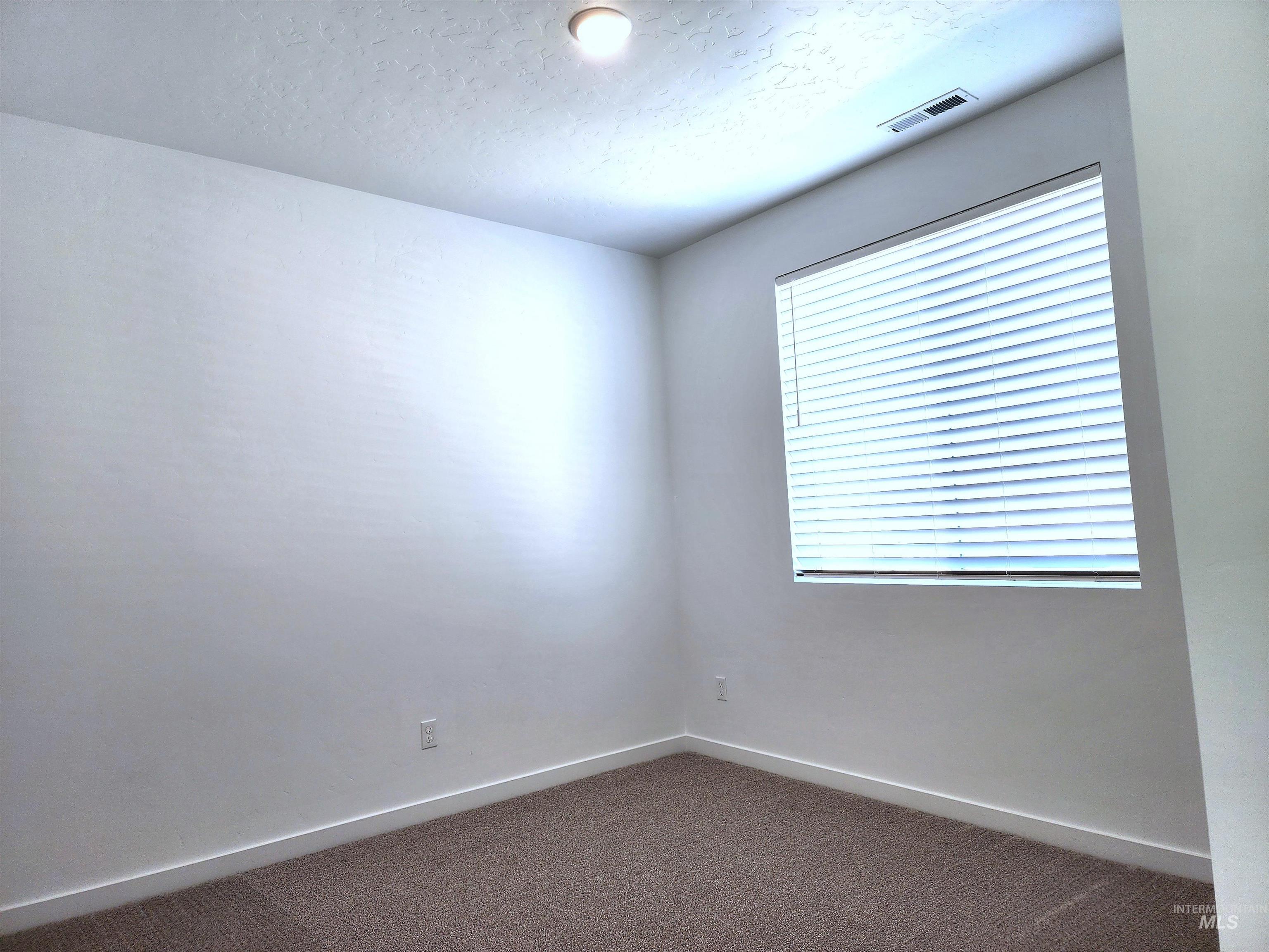 Carpeted empty room featuring baseboards and a textured ceiling