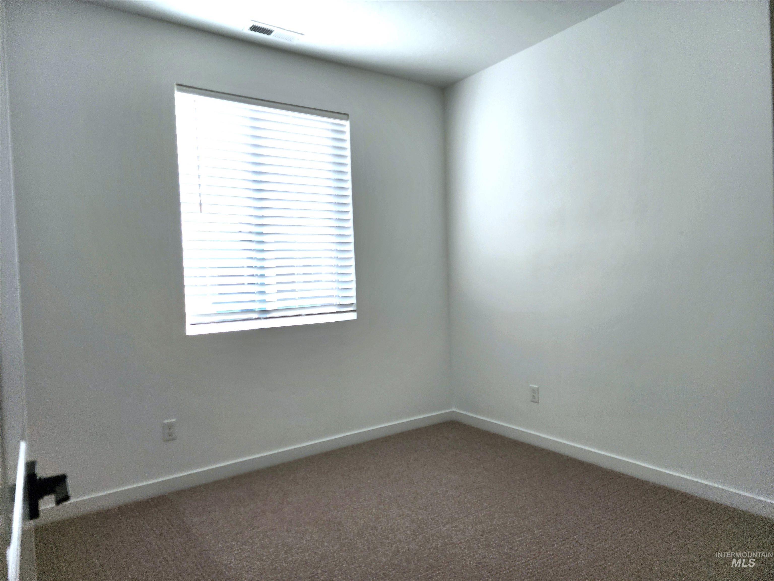Carpeted spare room featuring baseboards
