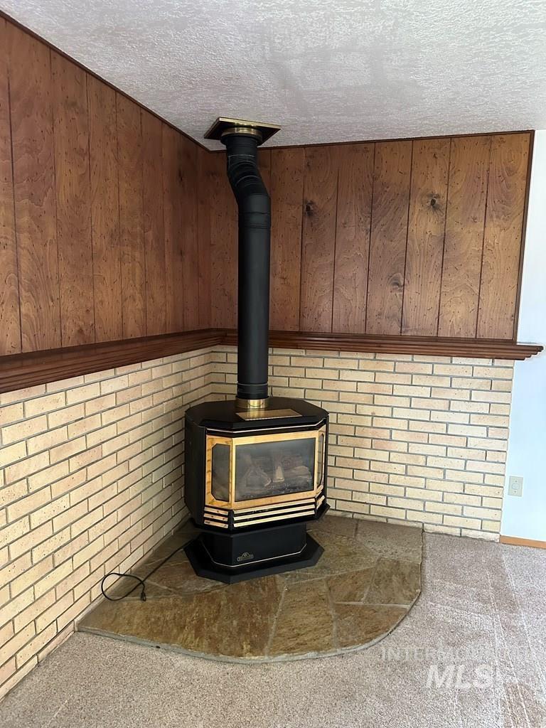 Detailed view of a wood stove, carpet floors, and a textured ceiling