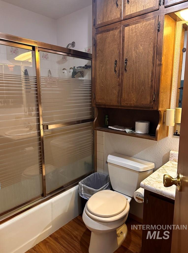 Bathroom with vanity, dark wood-style flooring, and shower / bath combination with glass door