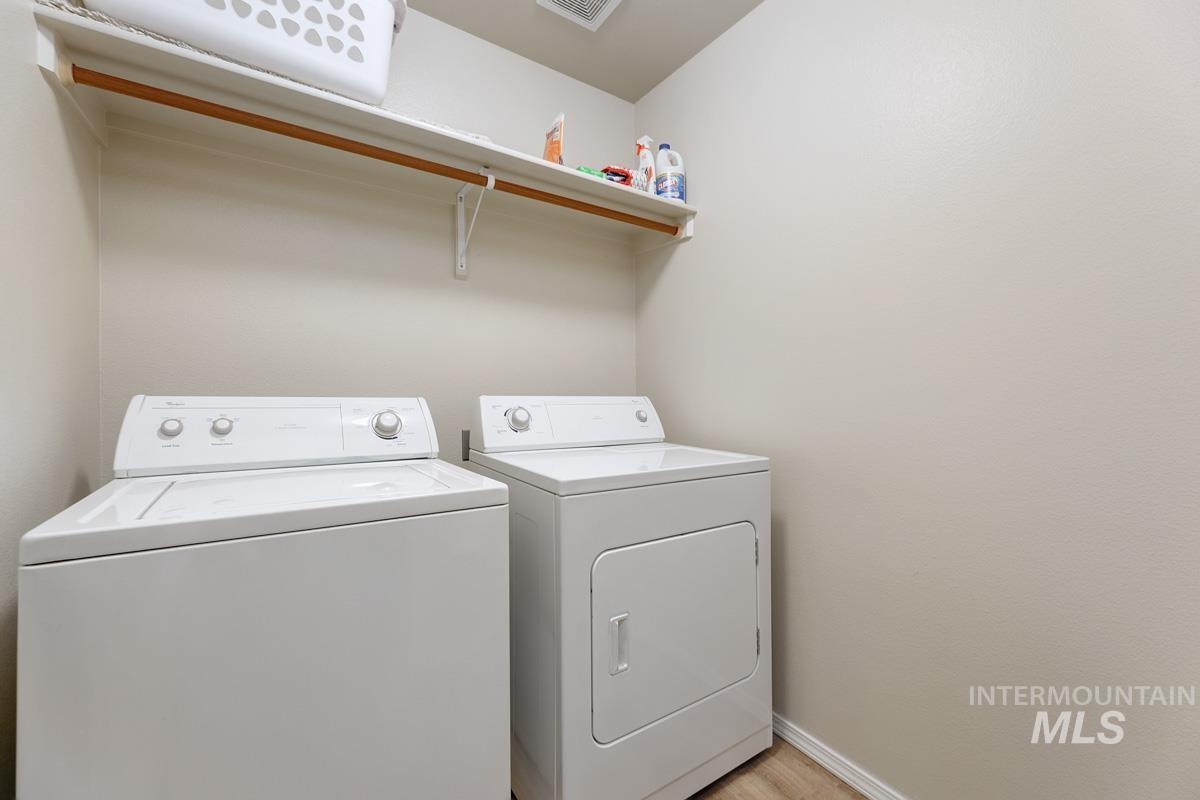 Laundry area with independent washer and dryer and light wood-type flooring