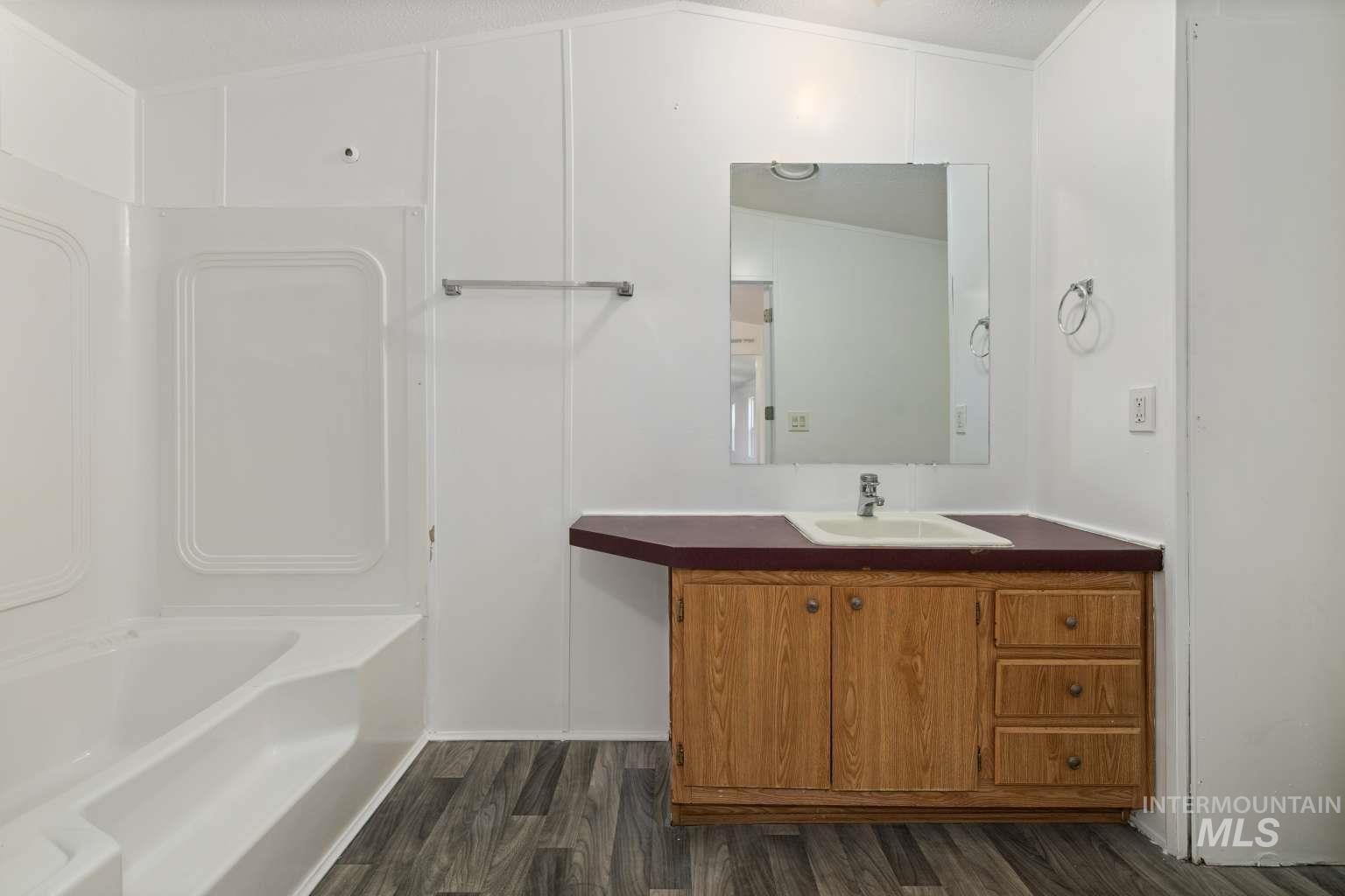 Full bath featuring dark wood-type flooring, vanity, bathtub / shower combination, and ornamental molding