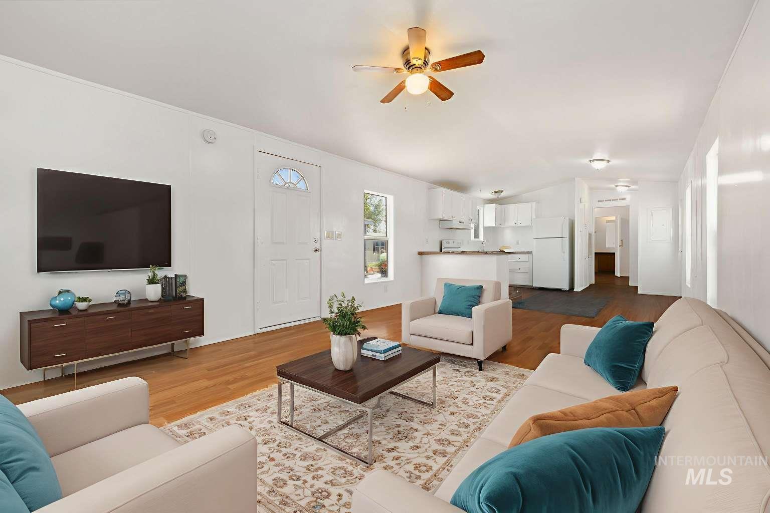 Living area with wood finished floors, a ceiling fan, and vaulted ceiling