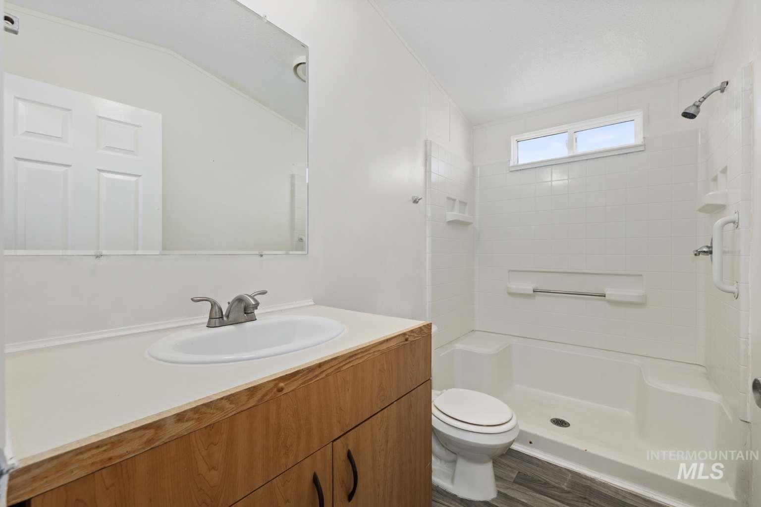 Full bathroom with vanity, a shower, and dark wood finished floors