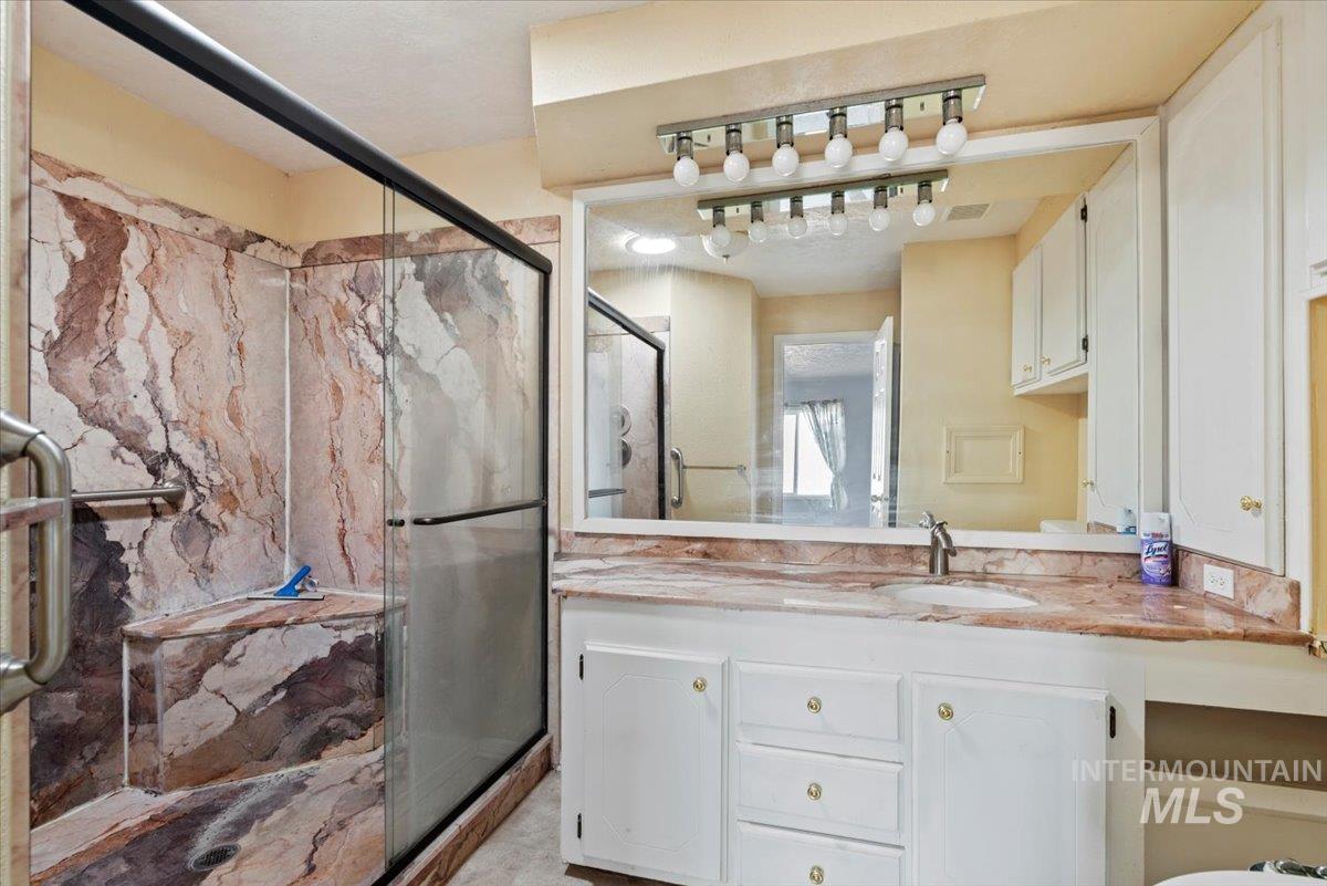 Bathroom with vanity and a marble finish shower