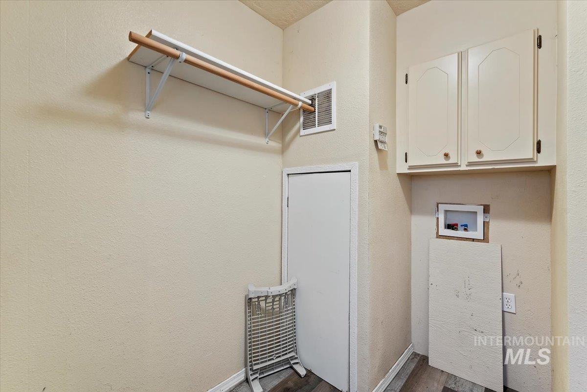 Washroom featuring a textured wall, dark wood-style floors, and washer hookup