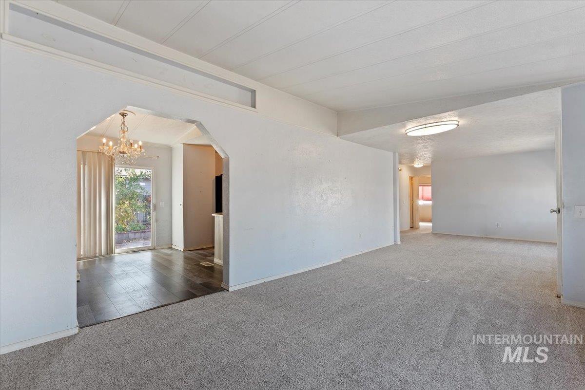 Empty room featuring carpet, arched walkways, and a chandelier