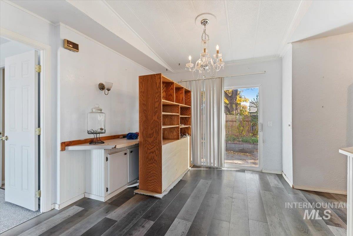 Unfurnished dining area featuring dark wood-style floors, crown molding, and a chandelier