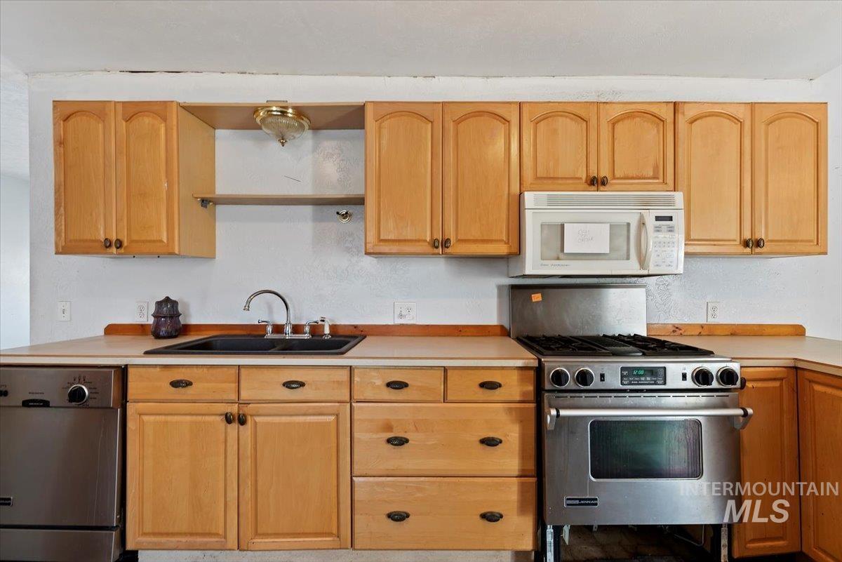 Kitchen featuring appliances with stainless steel finishes, light countertops, and light brown cabinets