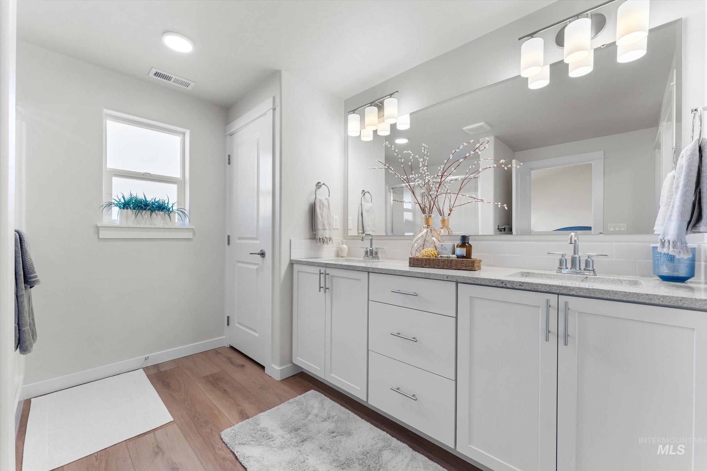Bathroom featuring double vanity and light wood finished floors