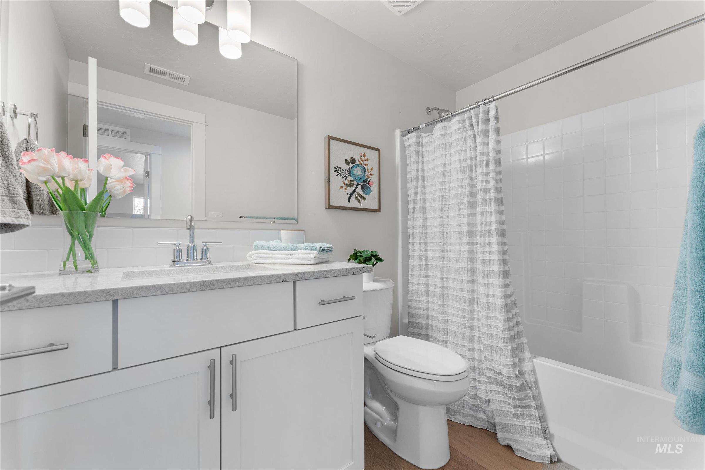 Full bathroom featuring vanity, shower / bath combo with shower curtain, and light wood-style floors