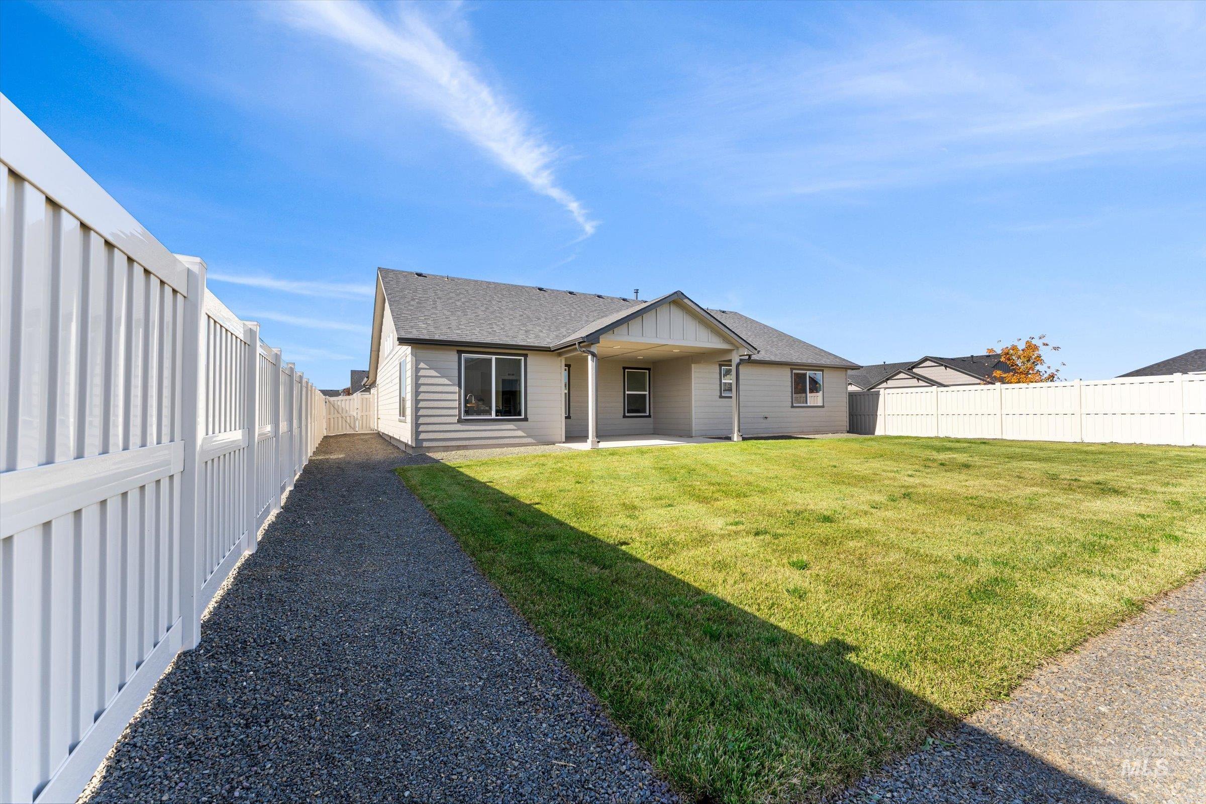 Rear view of house with a patio area, roof with shingles, a fenced backyard, and board and batten siding