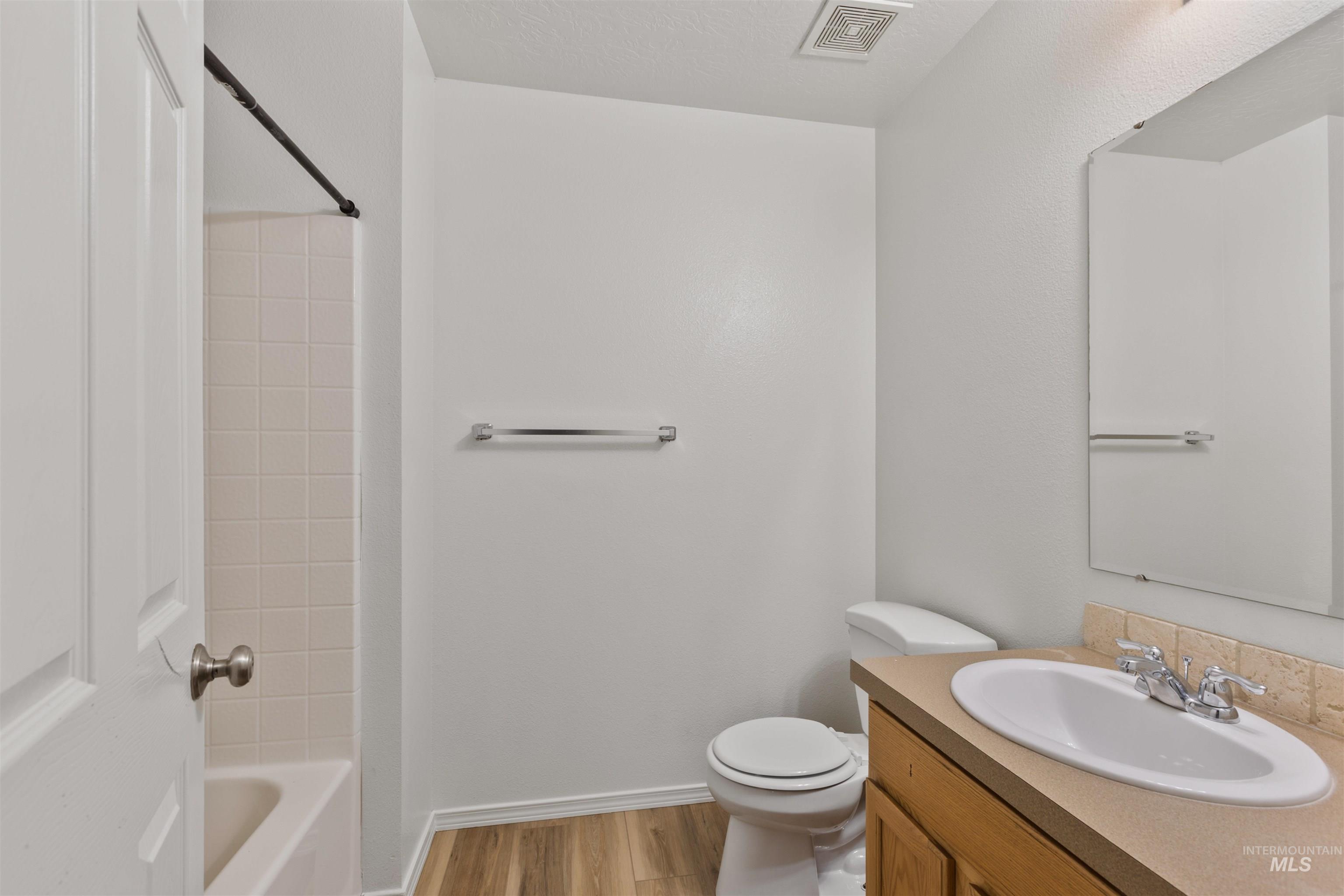 Full bathroom with light wood finished floors, vanity, and shower / bathtub combination