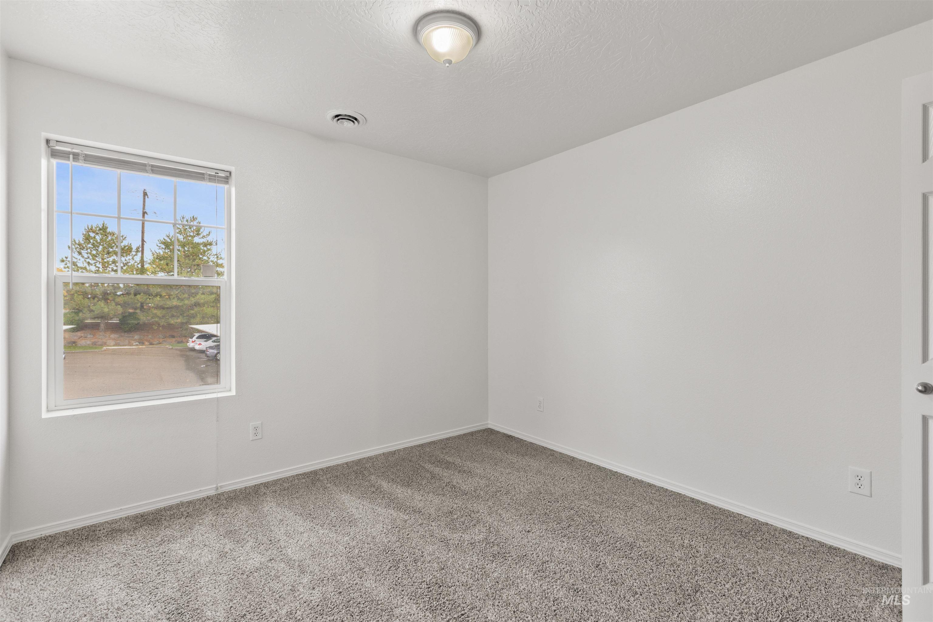 Empty room featuring carpet flooring and a textured ceiling