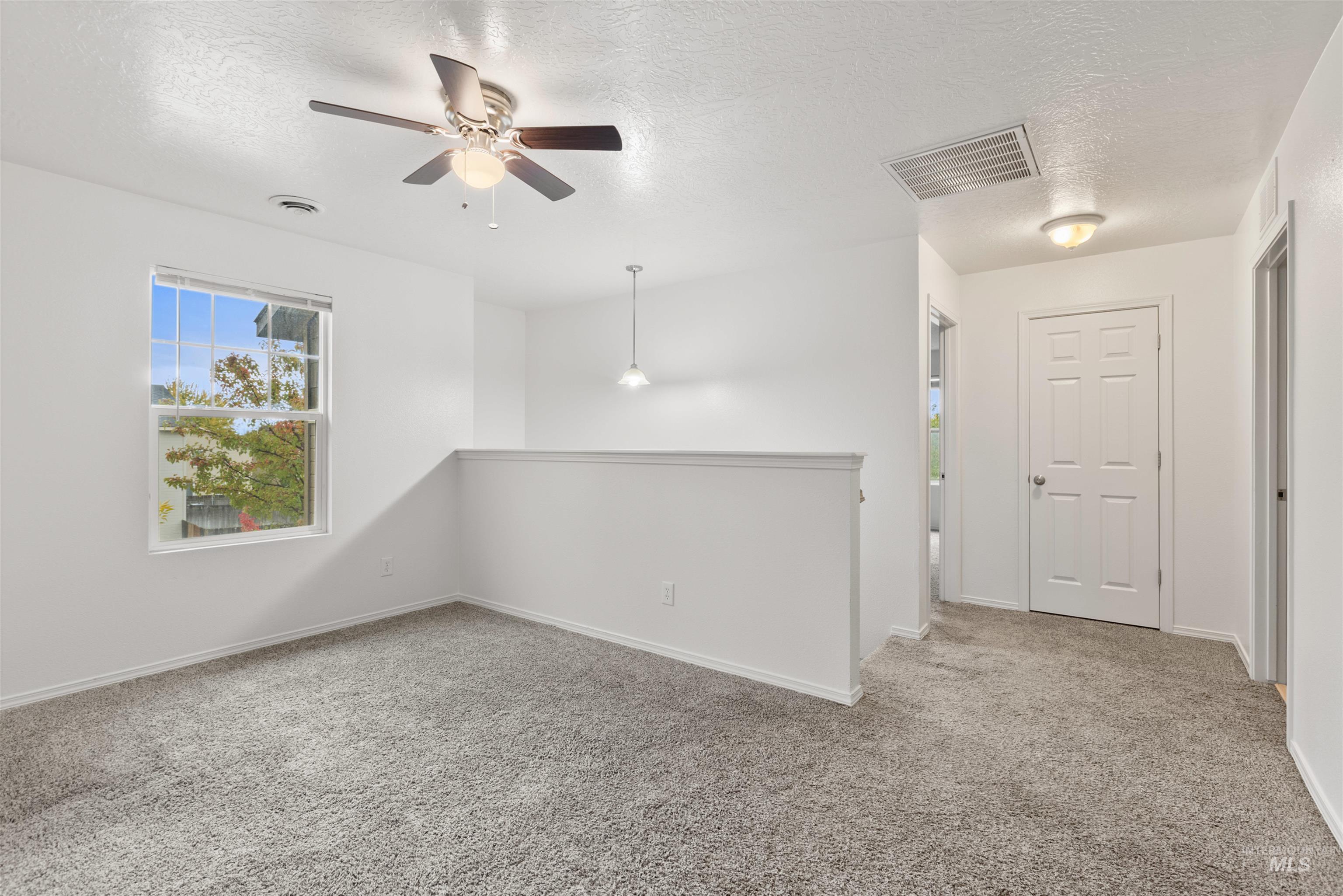 Empty room with a textured ceiling, light colored carpet, and ceiling fan