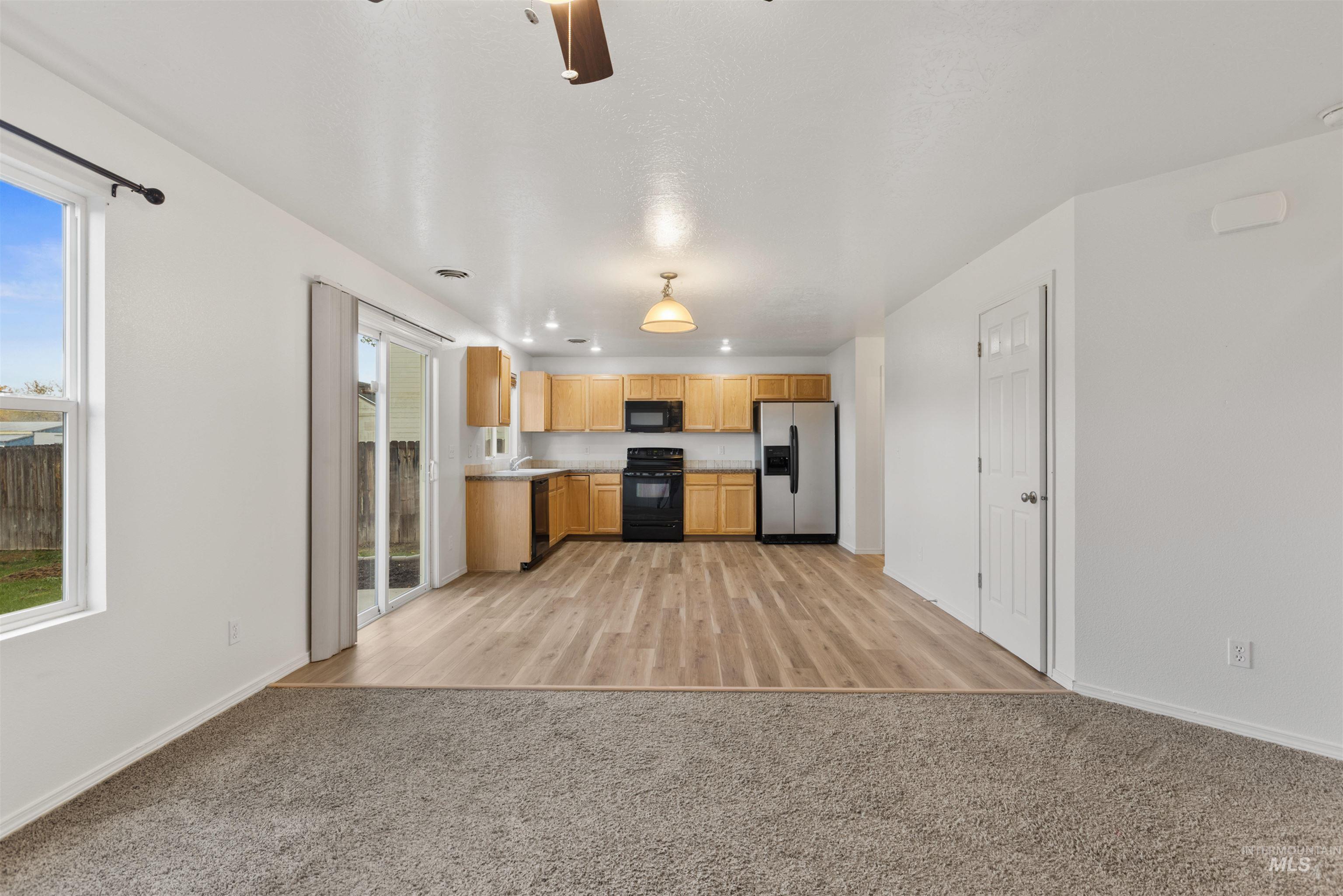 Kitchen featuring open floor plan, light countertops, black appliances, light carpet, and ceiling fan