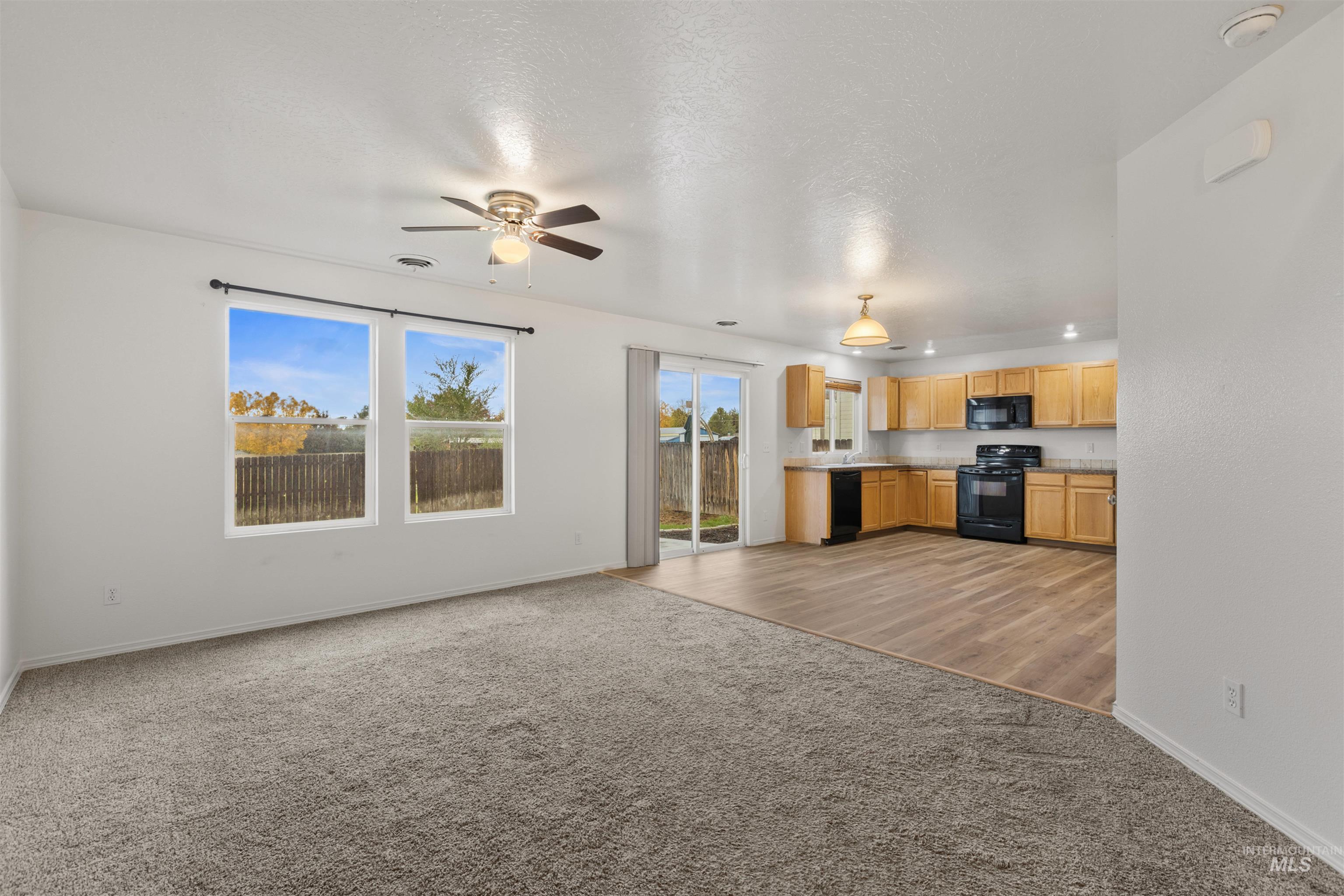 Unfurnished living room featuring light carpet and ceiling fan