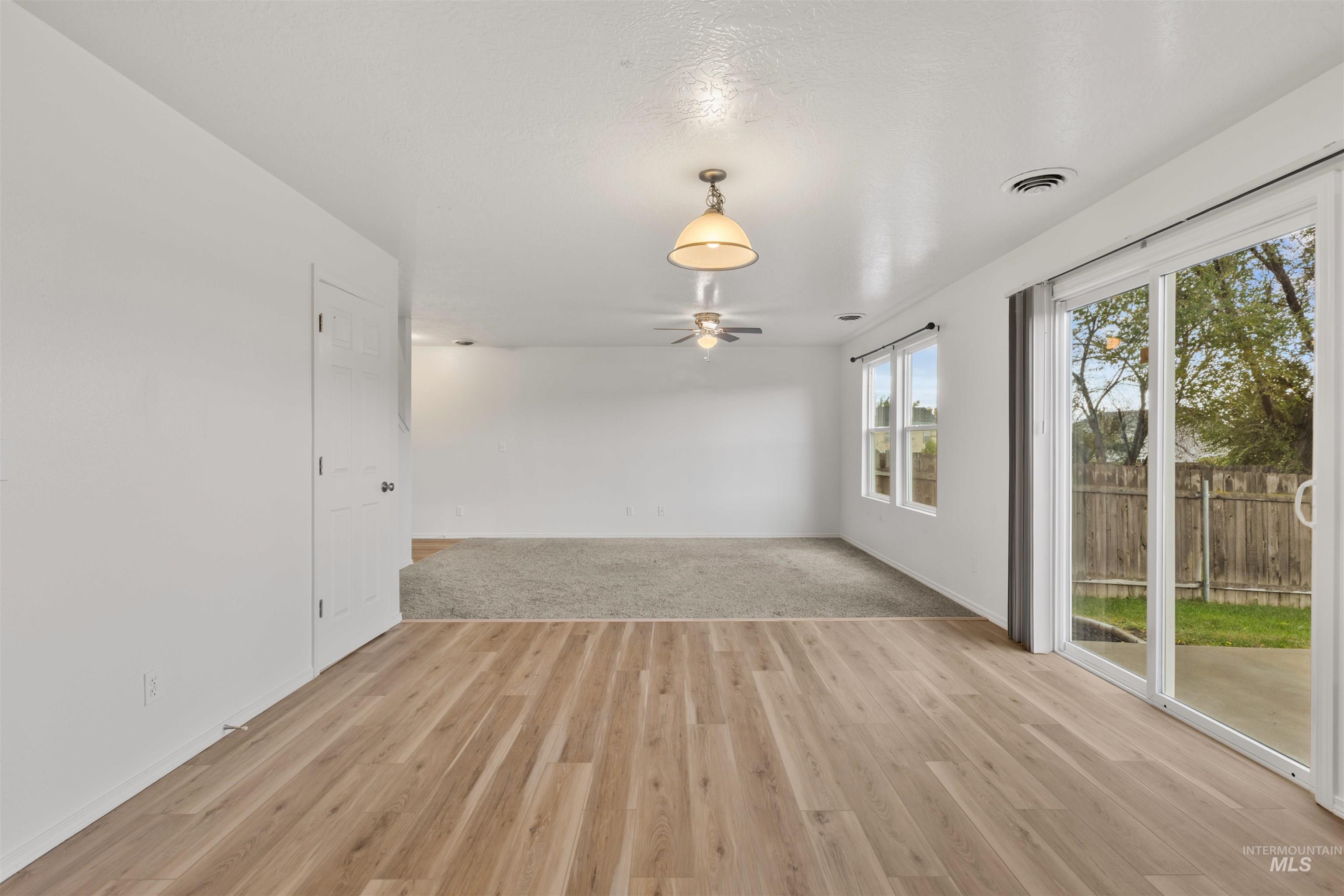 Unfurnished living room with light wood finished floors and ceiling fan
