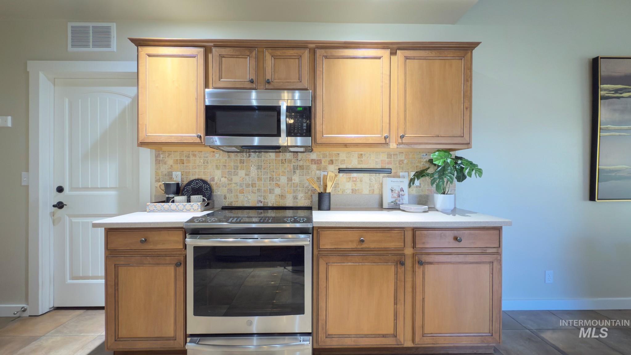 Kitchen with stainless steel appliances, backsplash, and brown cabinetry