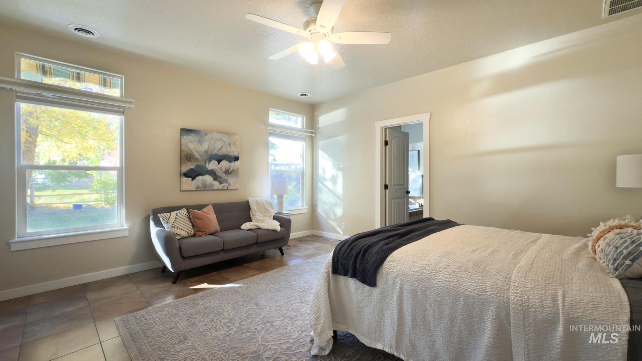 Bedroom featuring tile patterned floors, ceiling fan, and ensuite bathroom