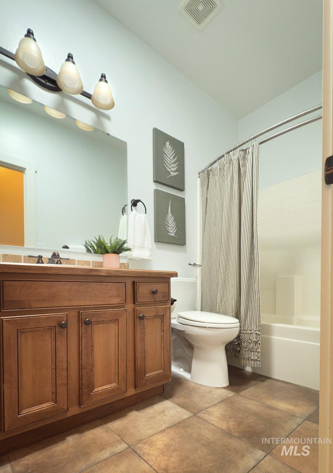 Full bath with vanity, shower / tub combo, and light tile patterned floors