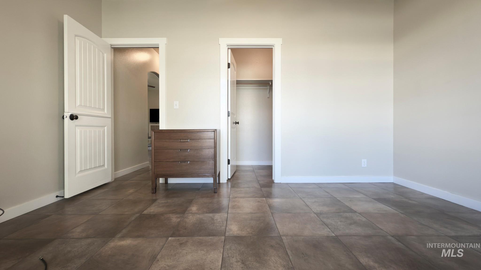 Unfurnished bedroom with a walk in closet and arched walkways