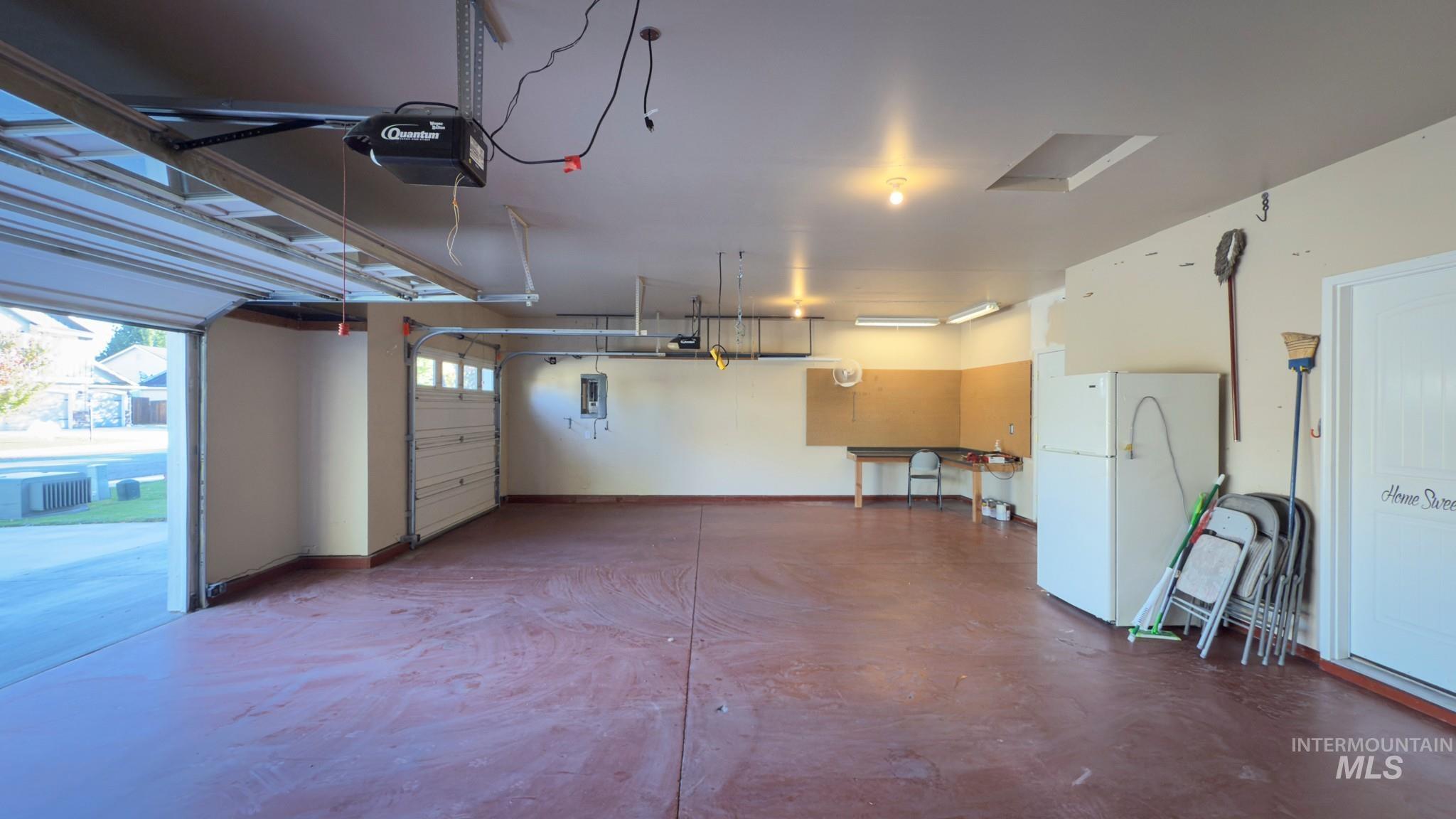 Garage featuring freestanding refrigerator and a garage door opener