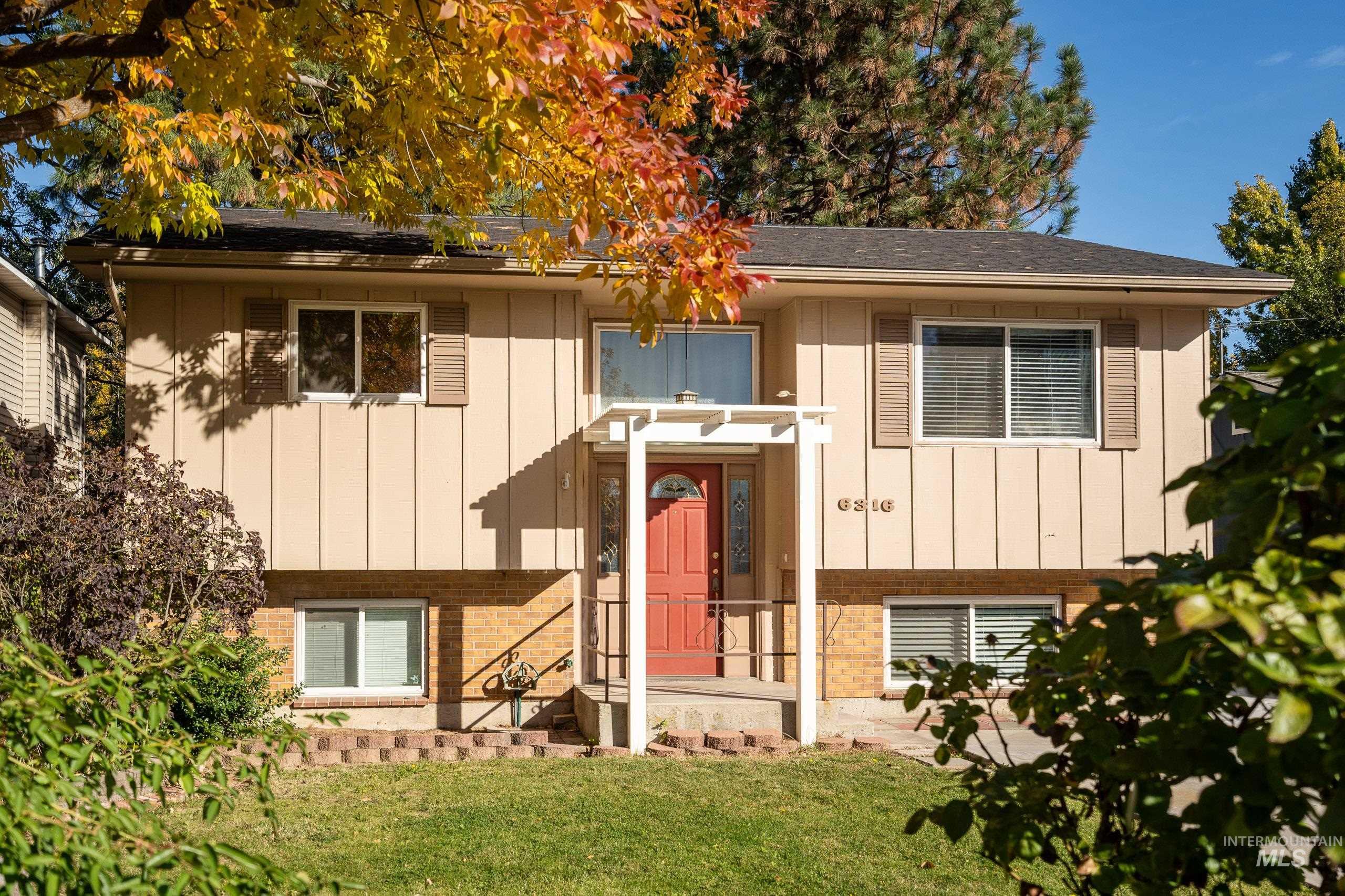 Raised ranch featuring board and batten siding, brick siding, and a front lawn