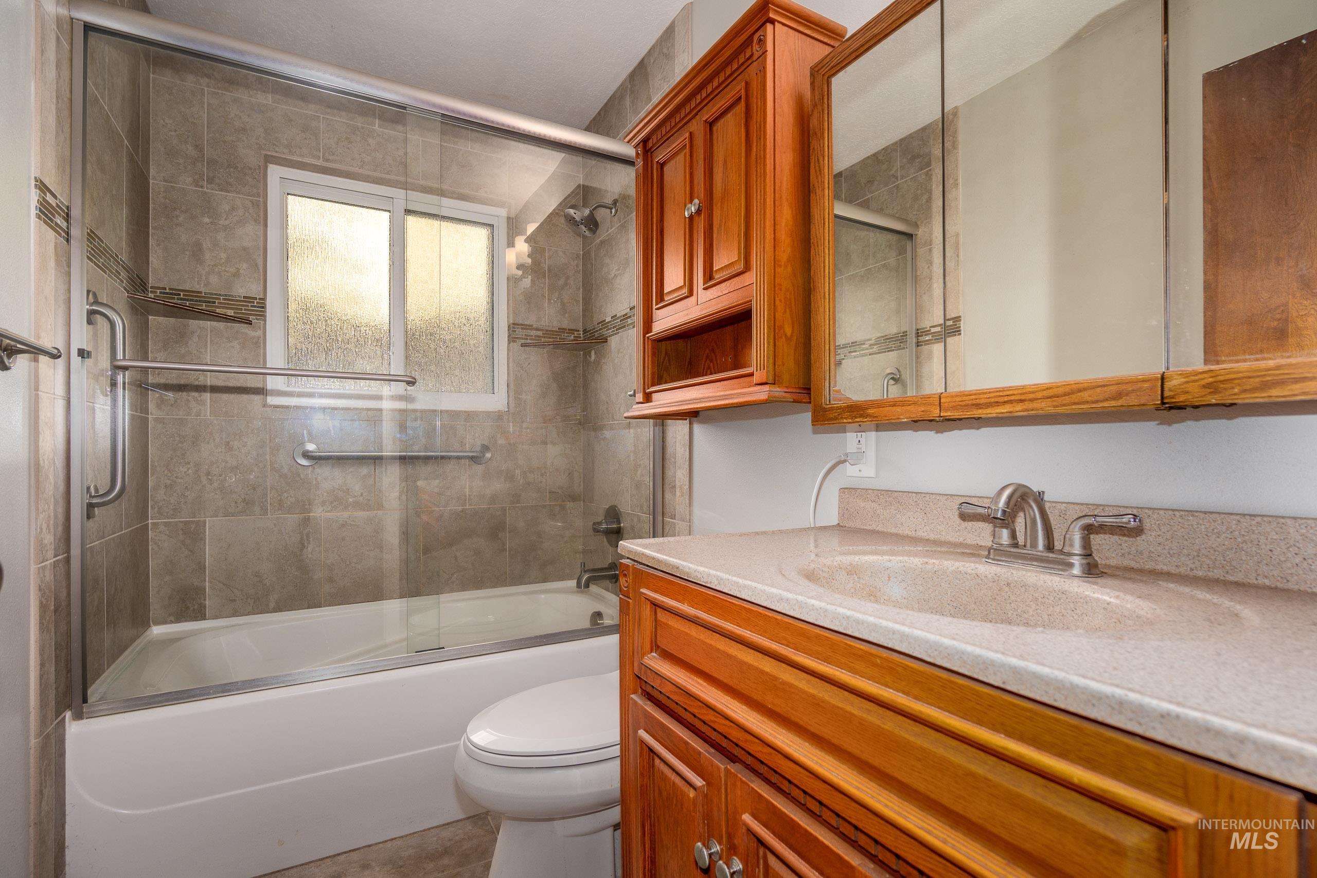 Bathroom featuring vanity, combined bath / shower with glass door, and light tile patterned flooring