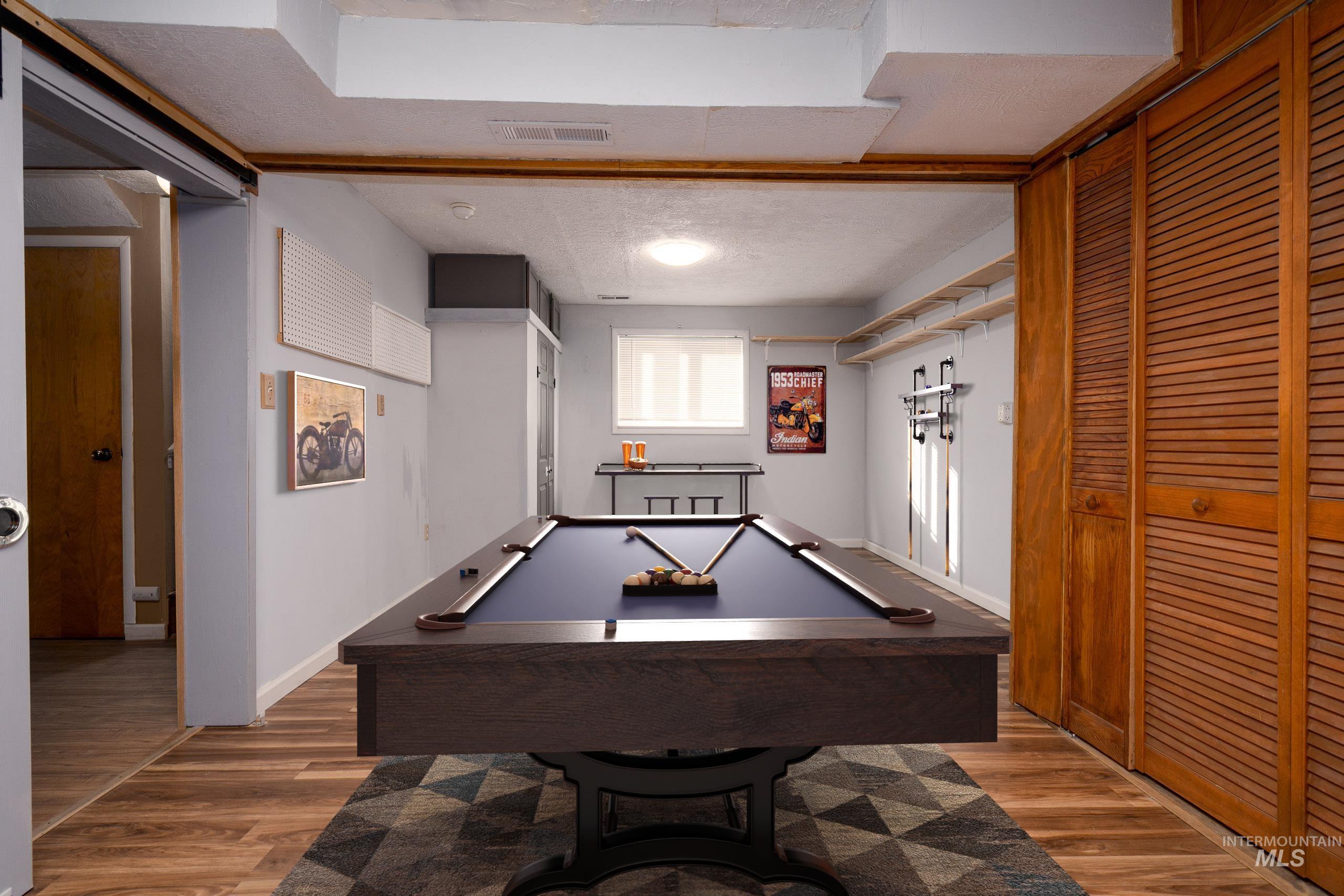 Game room featuring a textured ceiling, light wood-type flooring, and pool table