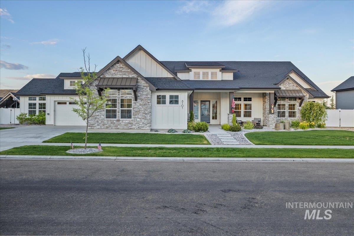 View of front facade featuring board and batten siding, stone siding, an attached garage, and concrete driveway