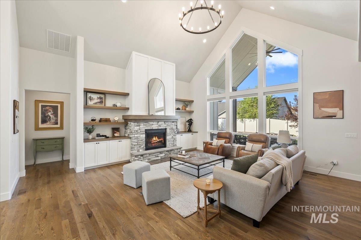 Living area featuring high vaulted ceiling, a fireplace, wood finished floors, and a chandelier