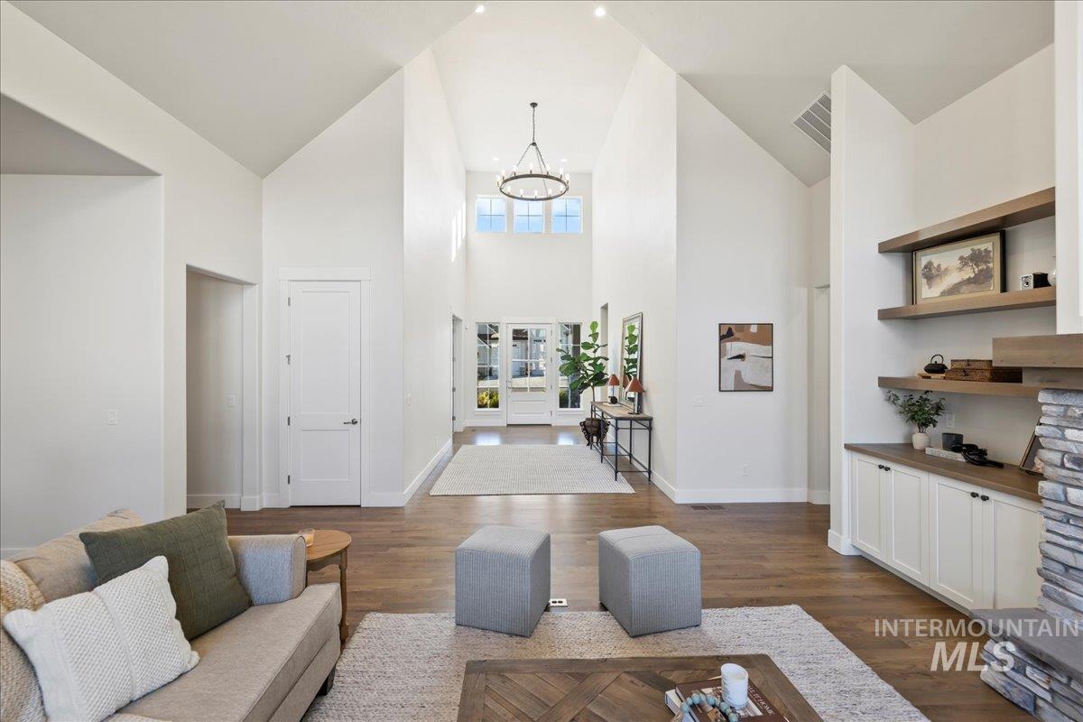 Living room with high vaulted ceiling, a chandelier, and dark wood-type flooring