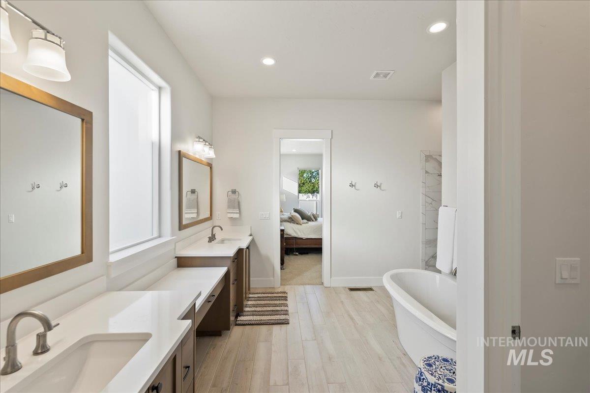 Bathroom featuring a freestanding tub, vanity, wood finished floors, ensuite bath, and recessed lighting