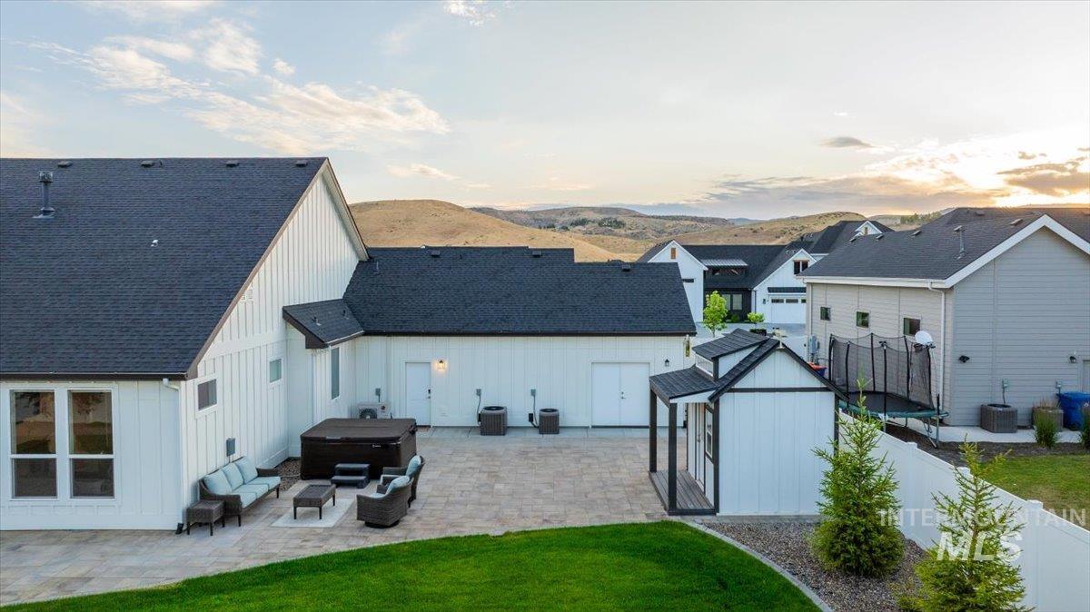 Back of house with a hot tub, board and batten siding, a patio, a shed, and a fenced backyard
