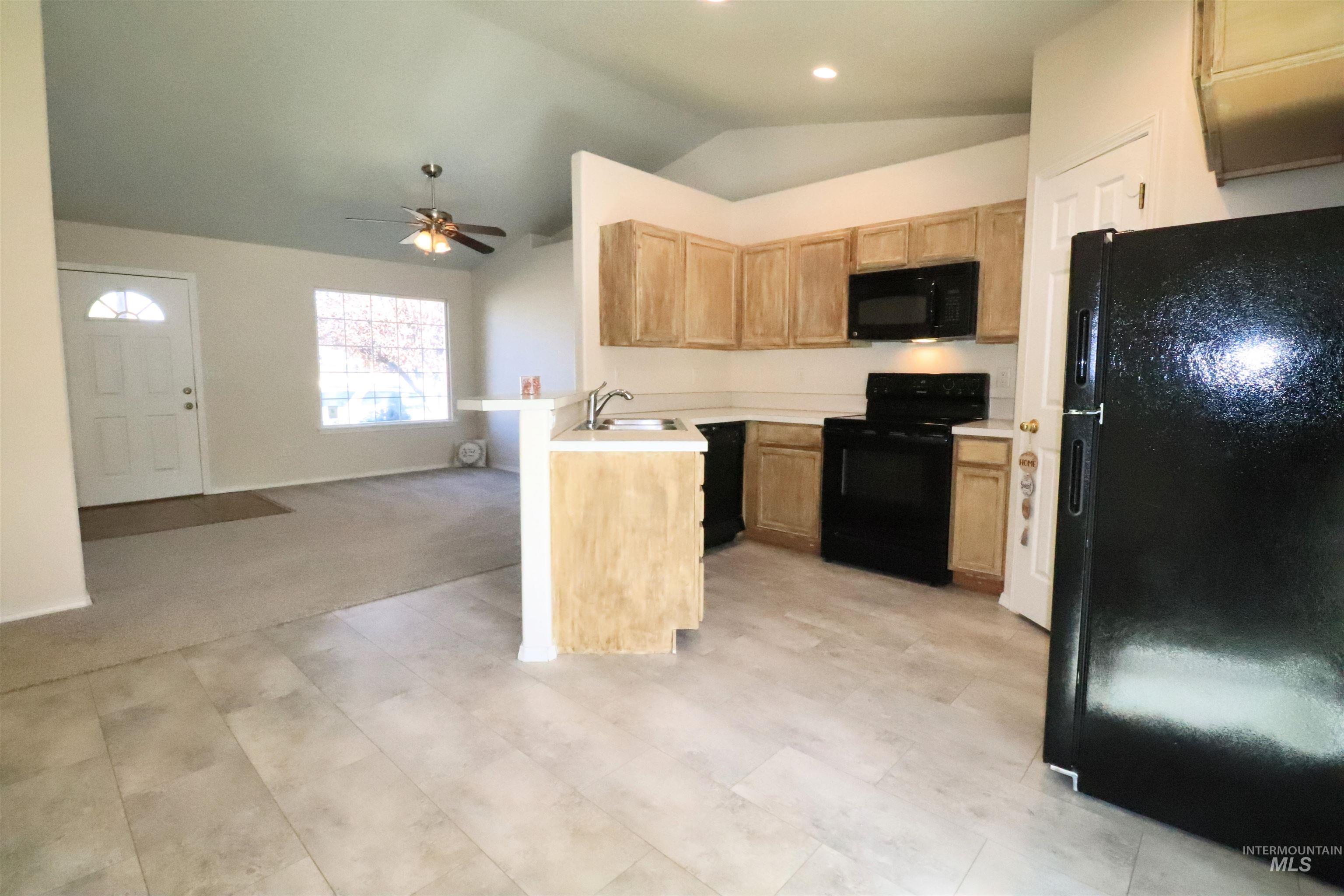 Kitchen featuring black appliances, vaulted ceiling, light countertops, open floor plan, and ceiling fan
